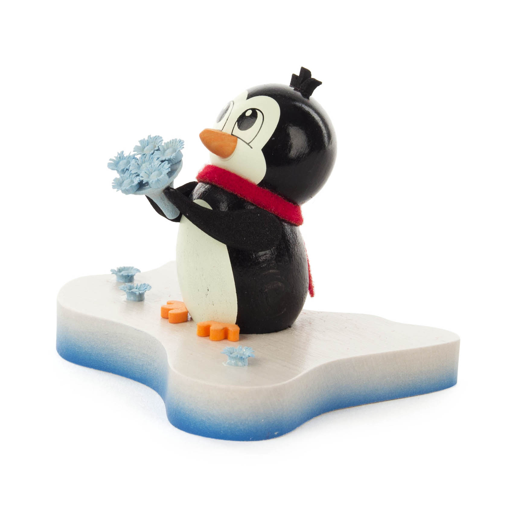 Figurine of a smiling penguin wearing a red scarf, holding blue ice flowers, standing on an ice-shaped platform.