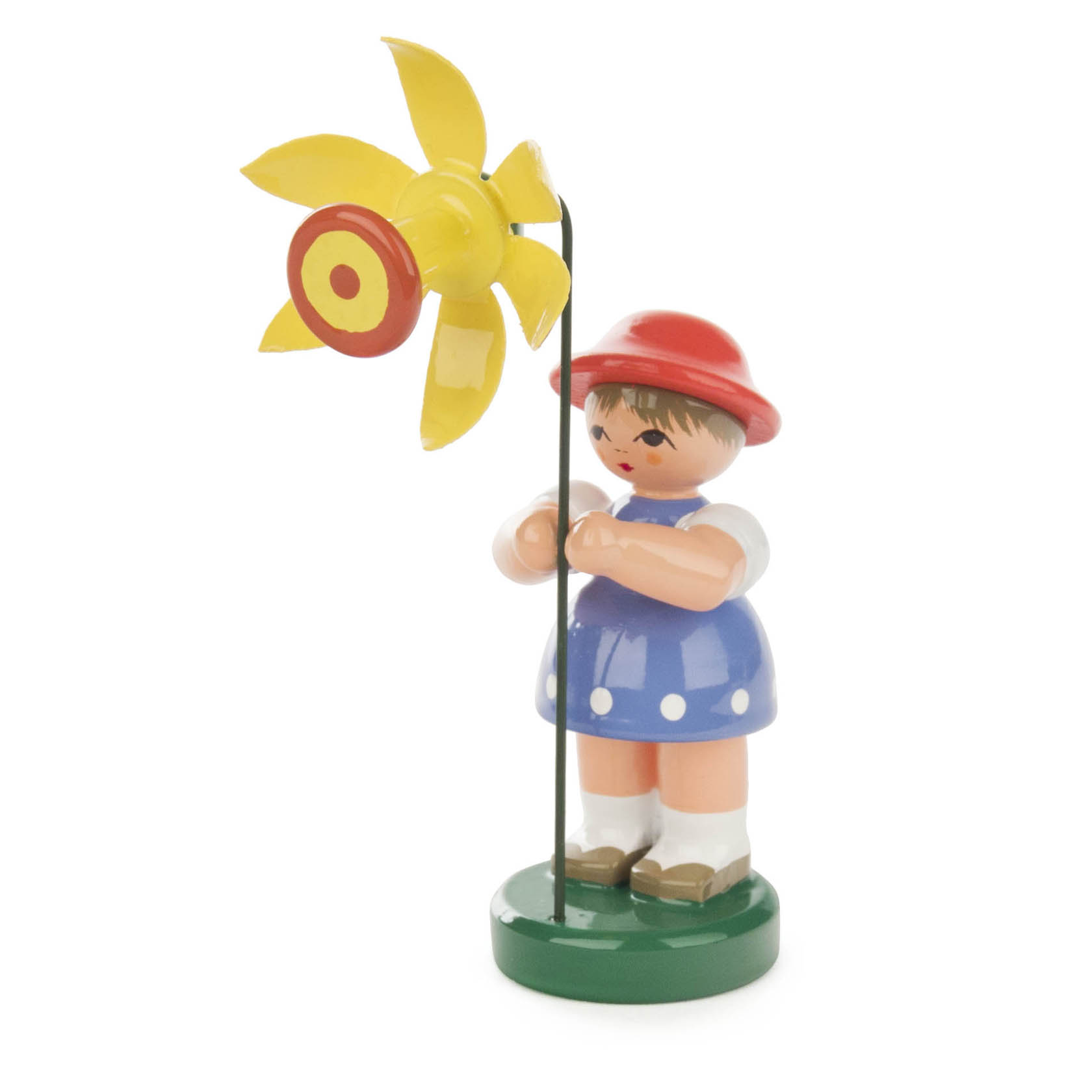Holzfigur eines Mädchens in einem blauen Kleid mit weißen Punkten und einem roten Hut. Sie hält eine gelbe Blume mit orangefarbenem Zentrum.