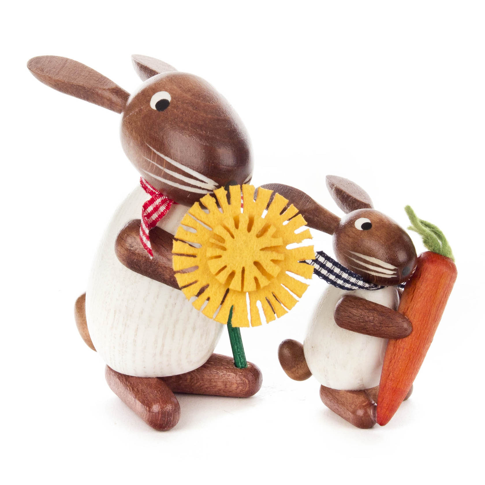 Two wooden figurines of rabbits, one large and one small. The large rabbit holds a yellow dandelion, and the small rabbit holds an orange carrot. Both have brown ears and white bodies.