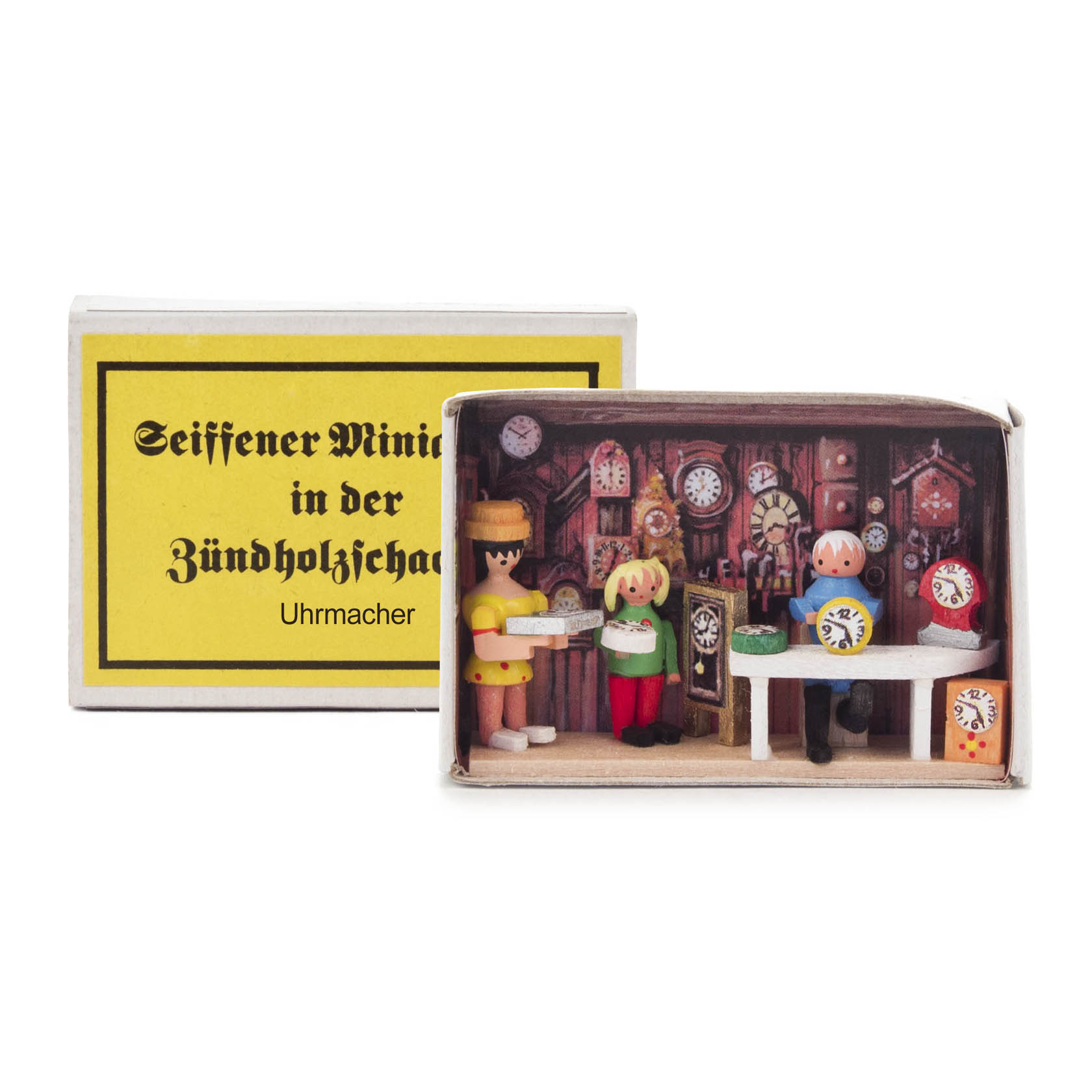 A small matchbox diorama depicting a watchmaker's workshop with miniature figures of a watchmaker and a customer, surrounded by various clock designs. im Dregeno Online Shop günstig kaufen