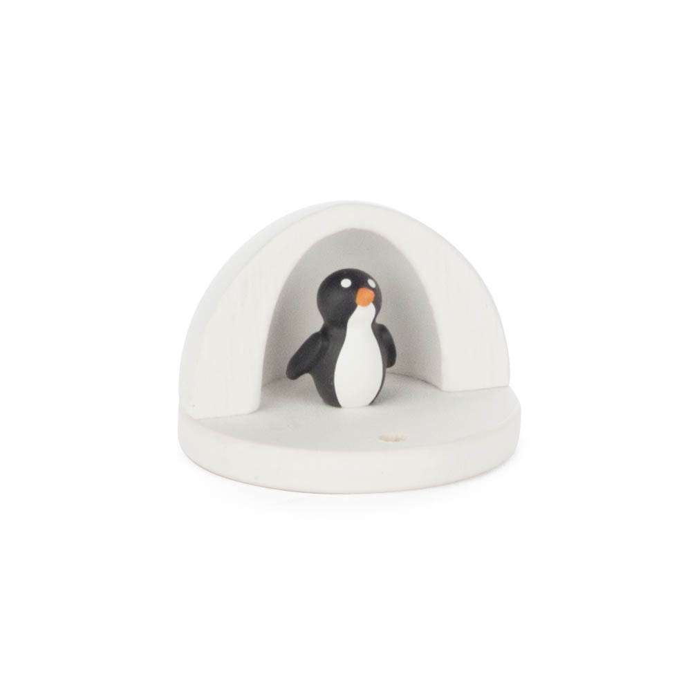 Eine kleine Pinguinfigur sitzt in einem halbkreisförmigen, schlichten, weißen Holzrahmen.