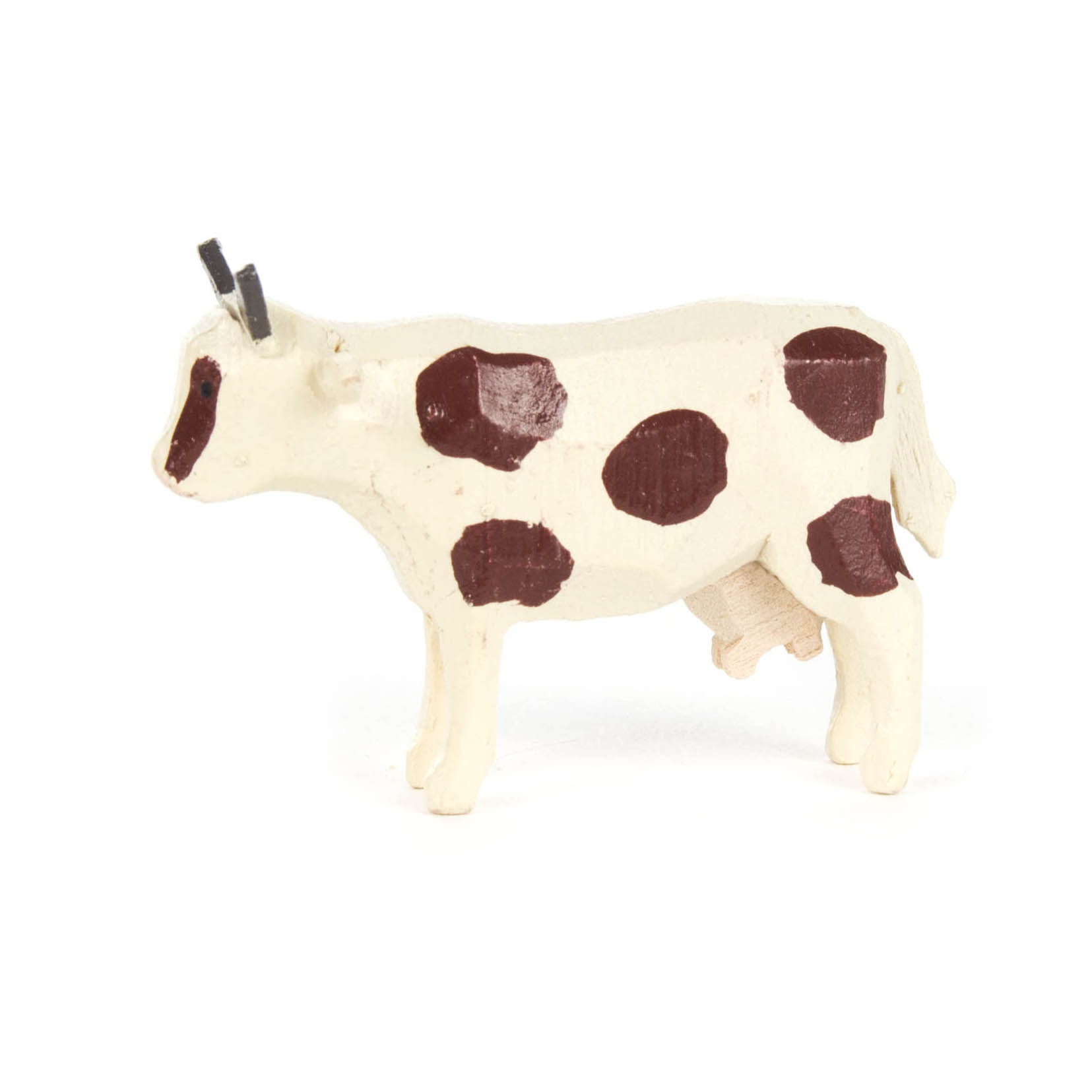 Ein Miniatur-Kuhmodell mit weißem Körper und braunen Flecken. Die Kuh hat kleine, gerade Hörner und einen Euter.