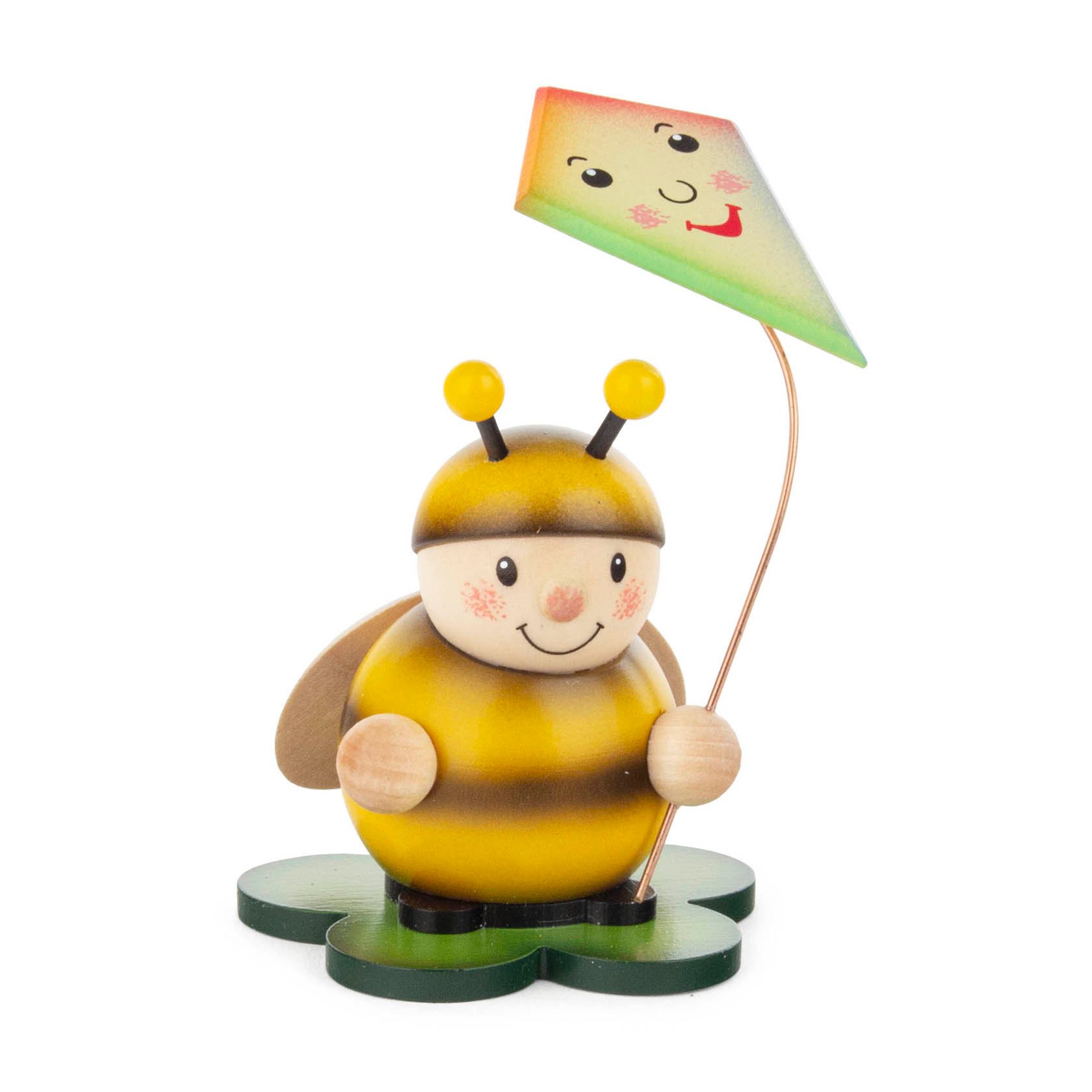 Wooden figure of a smiling bumblebee holding a colorful kite on a green base, designed for Vario candle holders.