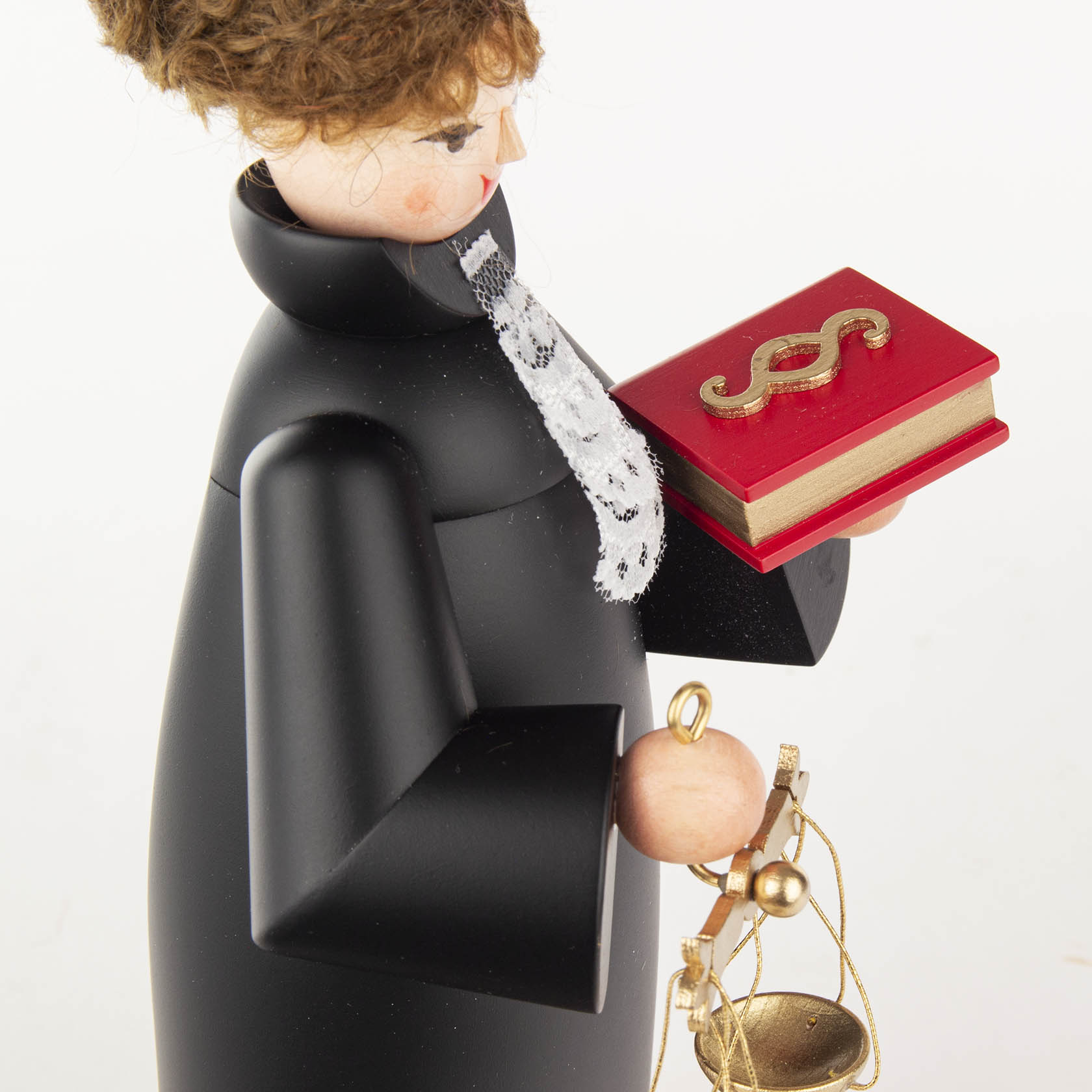 A wooden incense doll designed as a judge, wearing a black robe with lace collar, curly hair, holding a red book with a gold dollar symbol and justice scales.