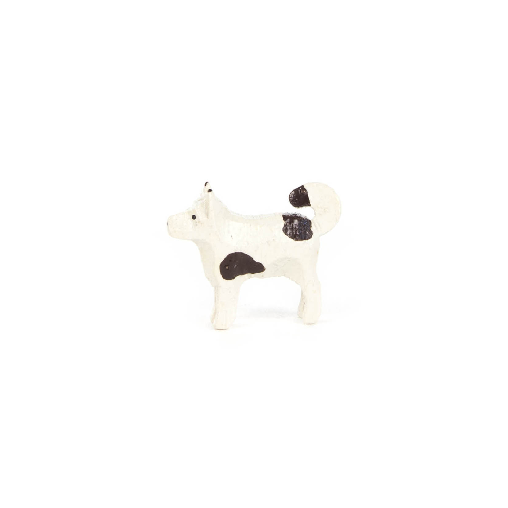 Kleine, weiße Keramikfigur eines Hundes mit schwarzen Flecken.