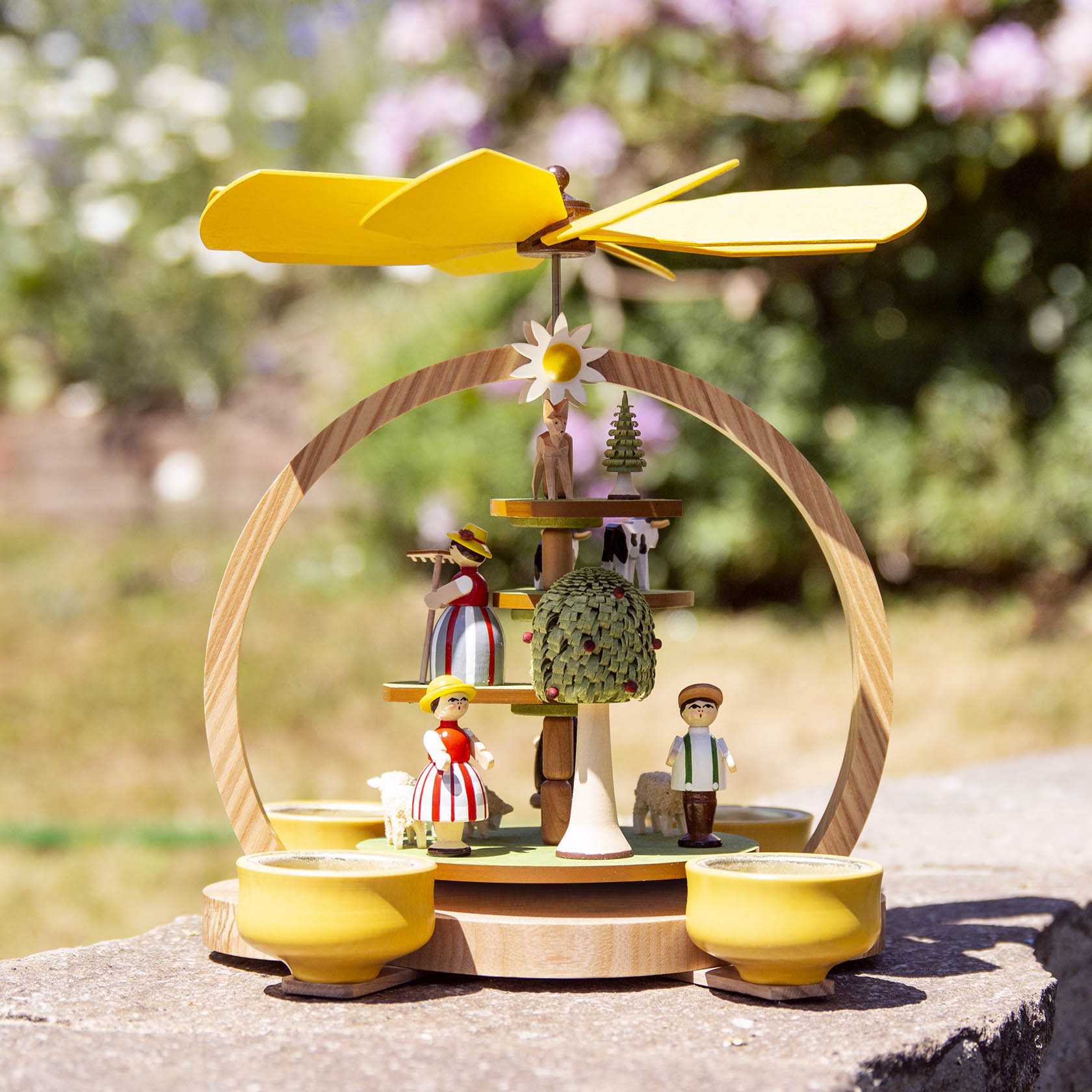 Holzpyramide mit gelben Flügeln, Figuren im Sommerwiesenmotiv und Platz für vier Teelichte.
