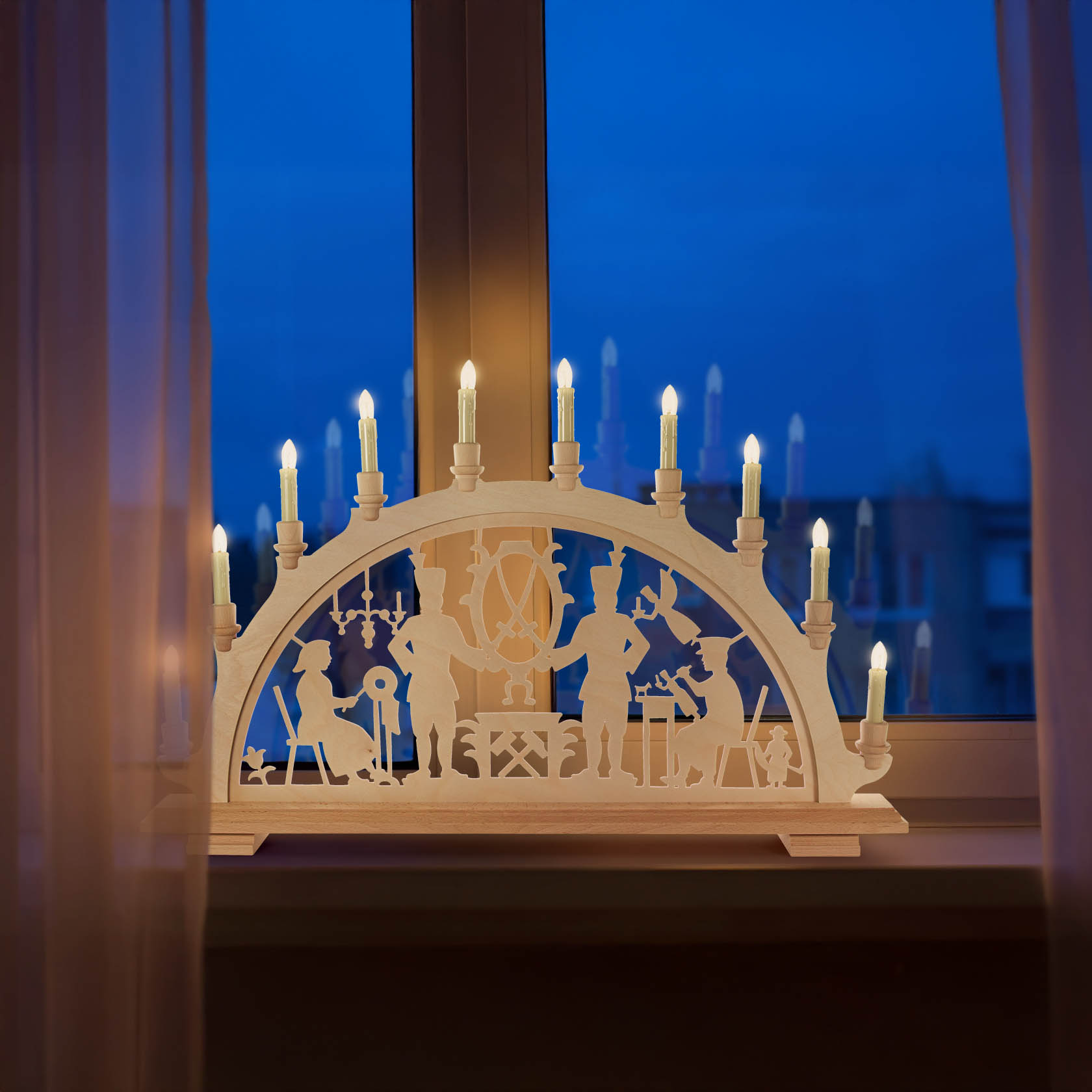 Illuminated arch candle holder with blacksmith motif, showing silhouettes of blacksmiths at work. Set on windowsill with deep blue evening sky.