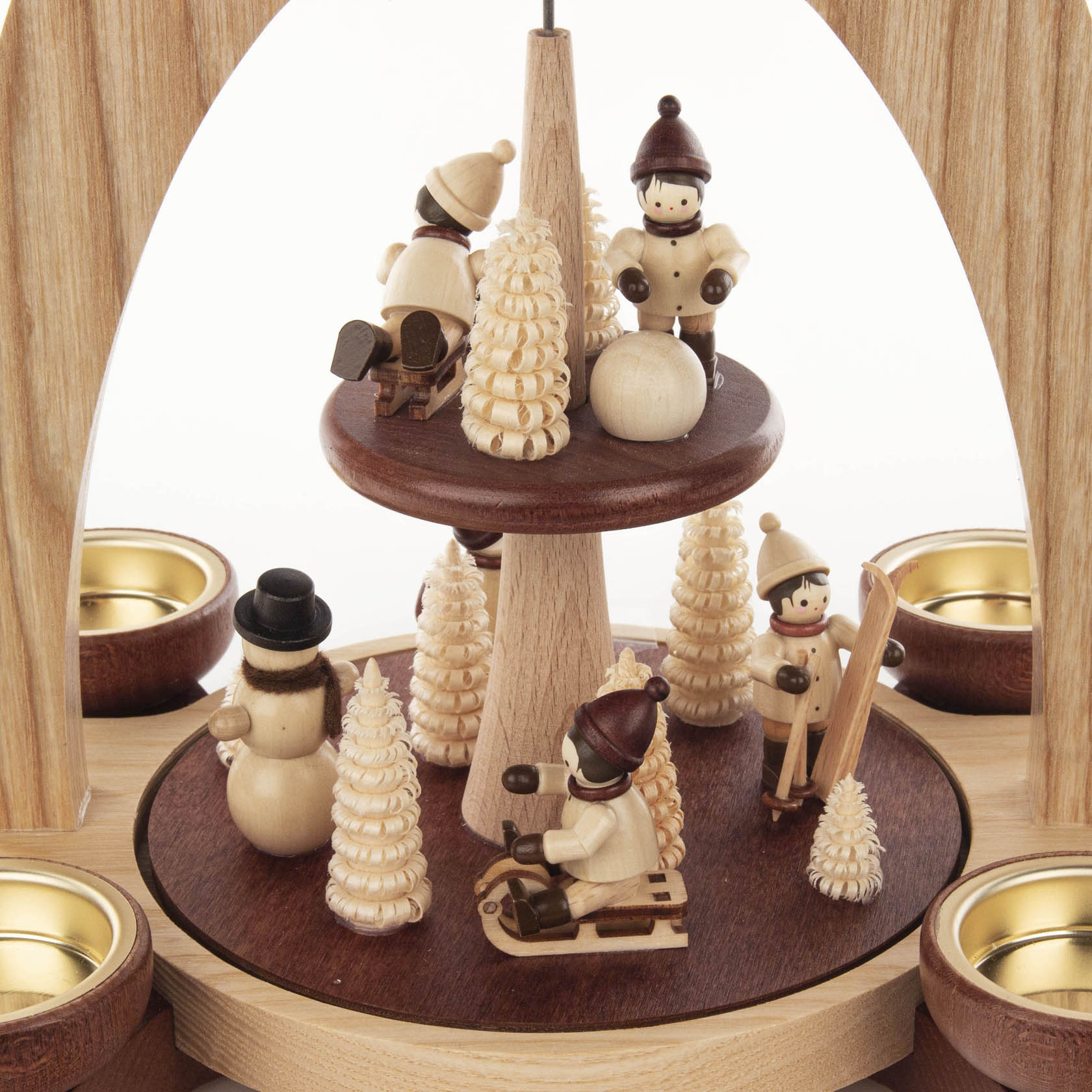 Two-tiered wooden pyramid featuring winter children figurines engaging in winter activities such as sledding and skiing, surrounded by small pine trees.