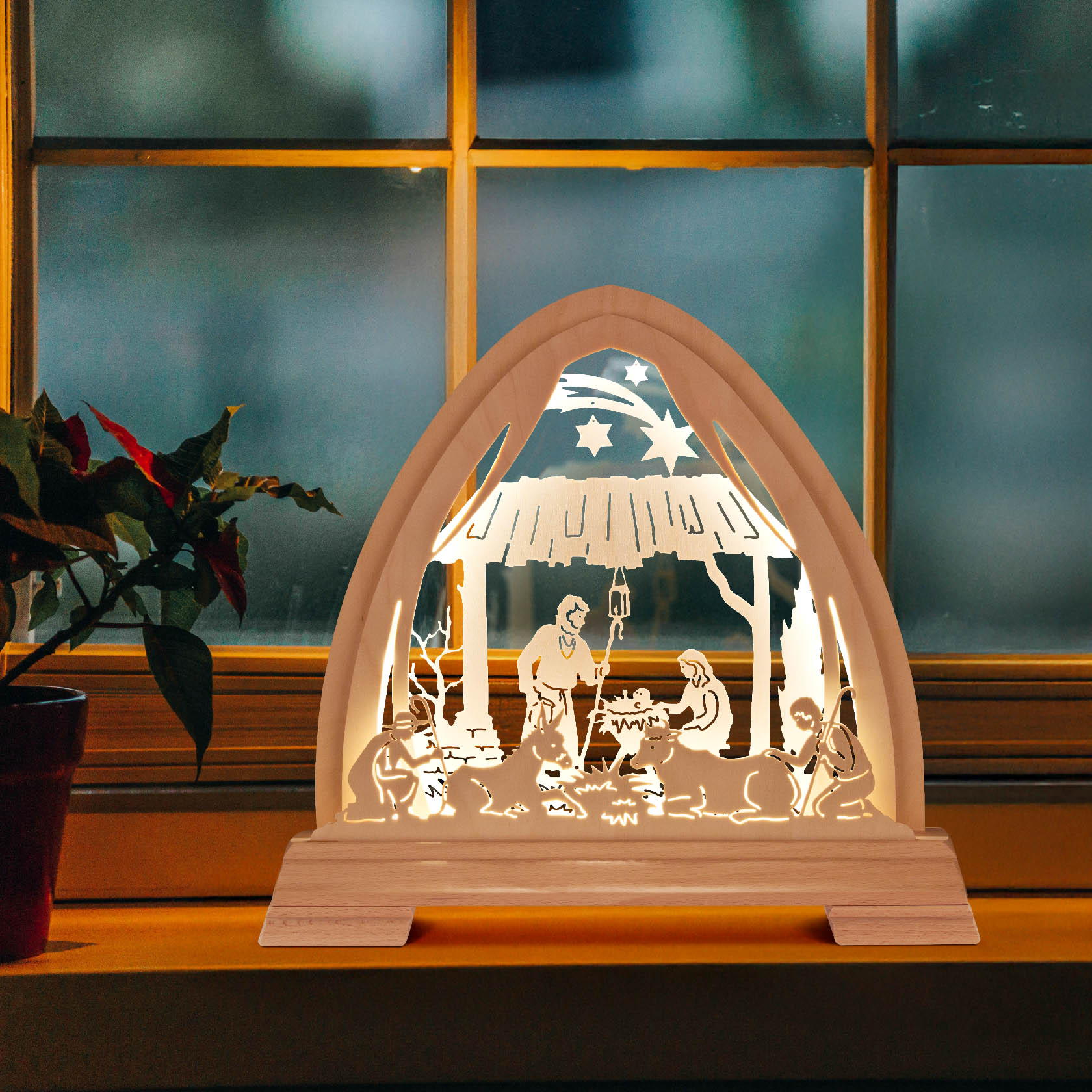 A Gothic arch depicting the Nativity scene with LED lighting, featuring Mary, Joseph, and Baby Jesus, set on a window sill.