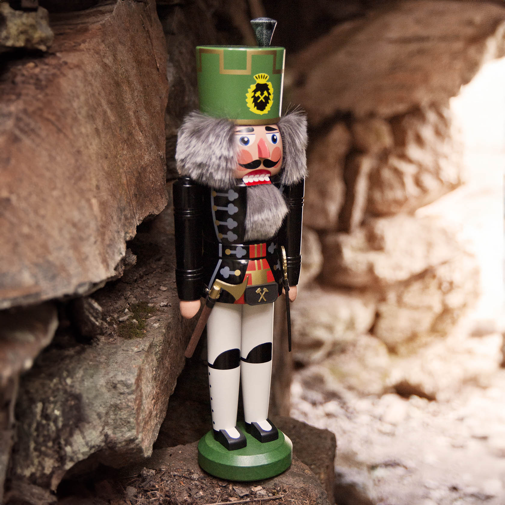 A black and white miner-themed nutcracker with a green hat, gray beard, and black boots, standing at 44 cm tall.
