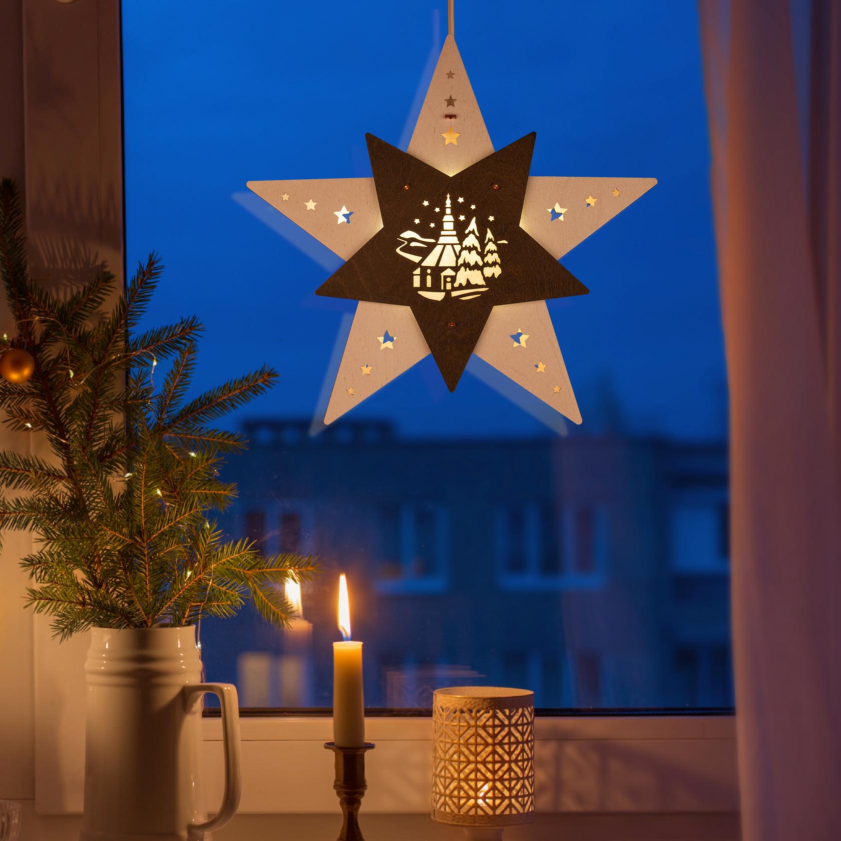 A star-shaped window decoration with LED lights, featuring a silhouette of the Seiffen Church in white and brown against a glowing evening backdrop.