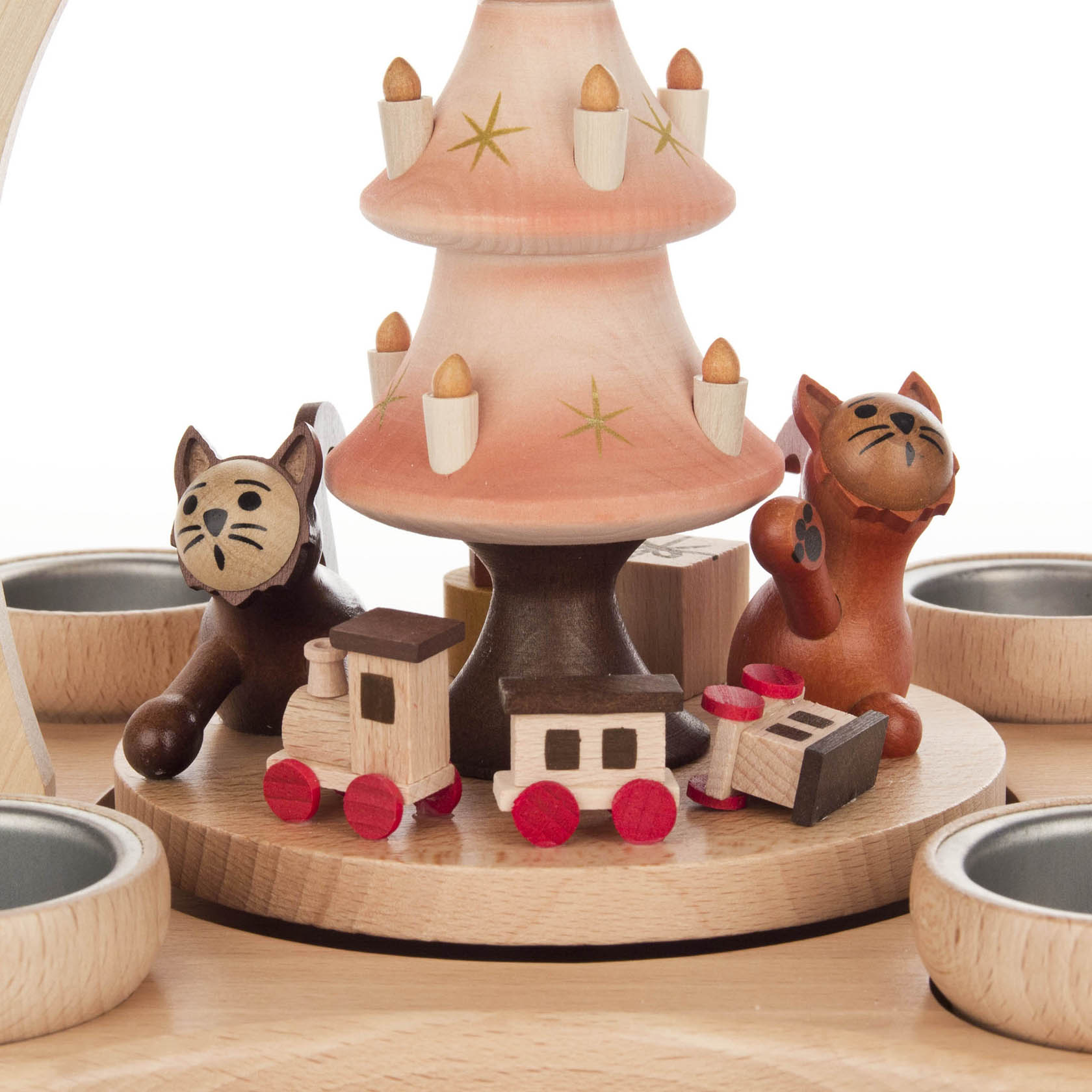 Drei Holzkatzen, die um einen Tannenbaum herum spielen. Zwei Katzen sind hellbraun, eine dunkelbraun. Es gibt kleine Holzzüge und Teelichthalter.