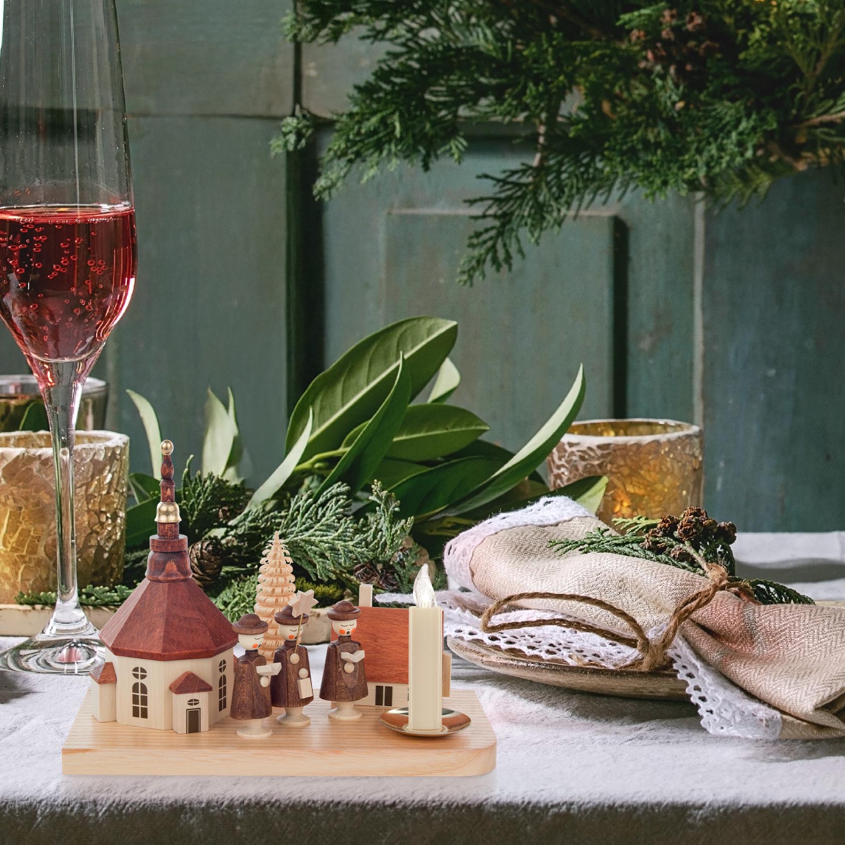 A Christmas-themed candle holder featuring a model of the Seiffen Church, a house, and a carol singer with a candle holder fitting a 14mm candle.