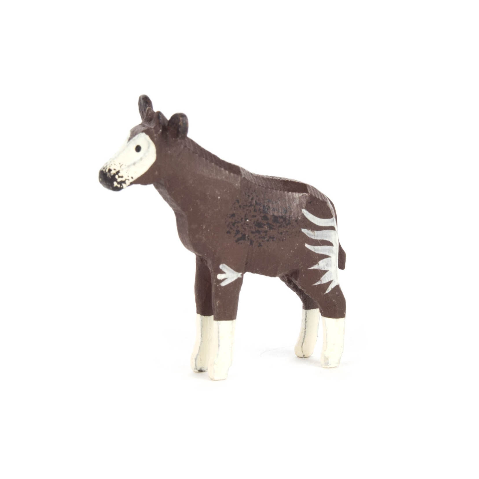 Kleine Plastikfigur eines Okapis, brauner Körper mit weißen Streifen an Beinen und Gesicht, stehend auf weißen Beinen.