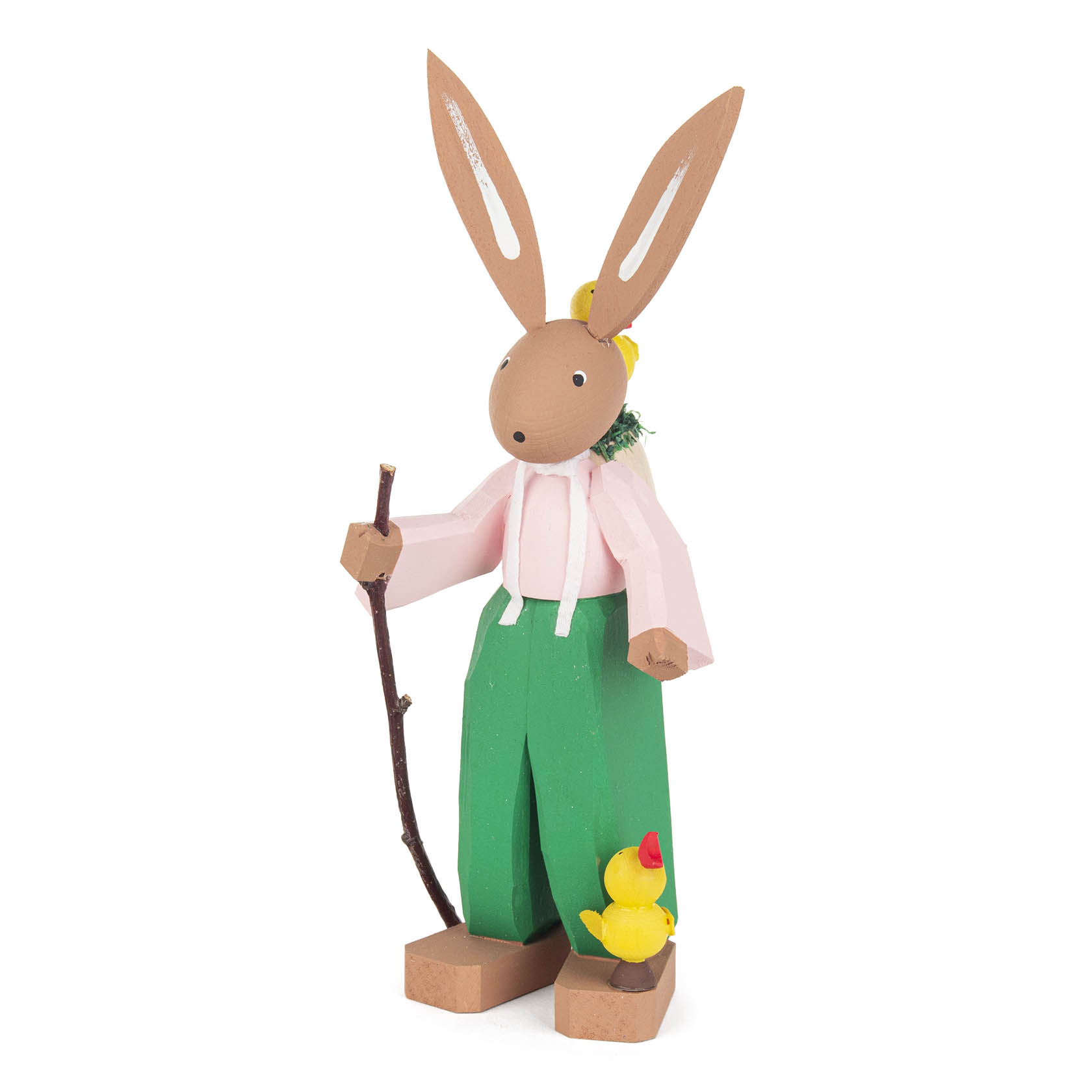 A wooden Easter bunny with long ears, wearing a pink shirt and green pants, holding a stick, and standing next to a small yellow chick.