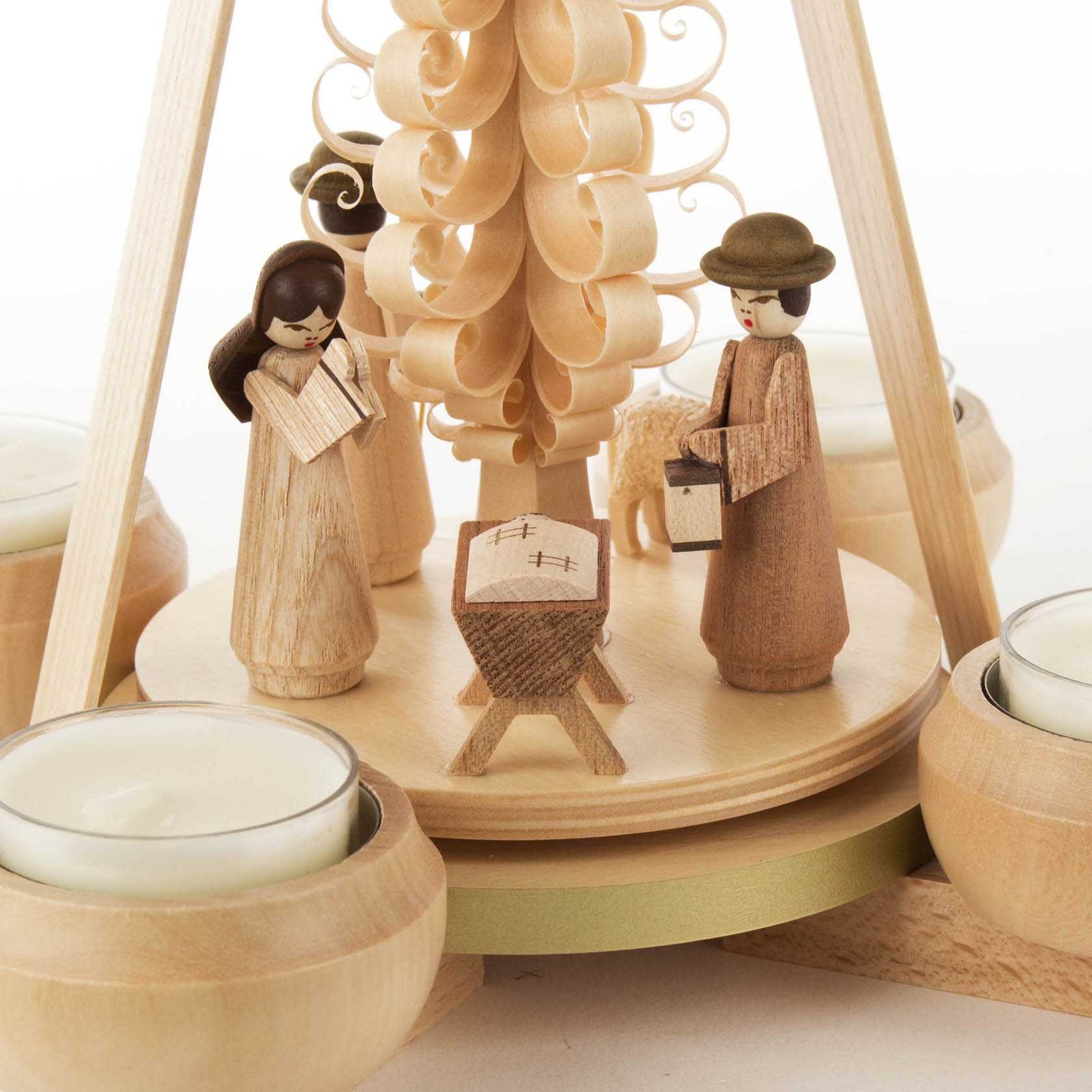 Wooden pyramid with nativity scene, featuring figurines of Mary, Joseph, baby Jesus in a crib, and tealight candle holders around the base.
