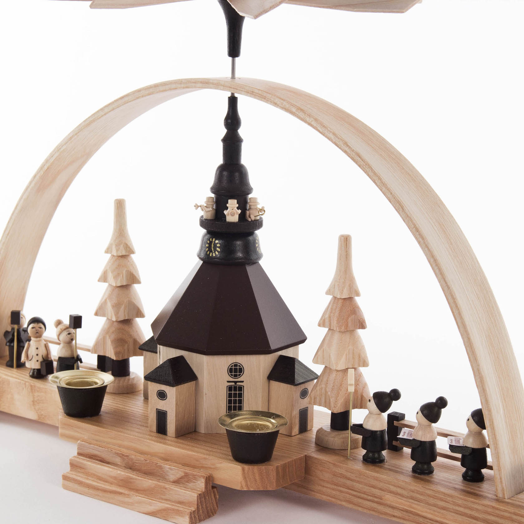 Ein Pyramidenschwibbogen mit der Seiffener Kirche, flankiert von zwei großen Pyramidenbäumen. Links stehen zwei Laternenkinder, rechts eine Kurrende-Gruppe.