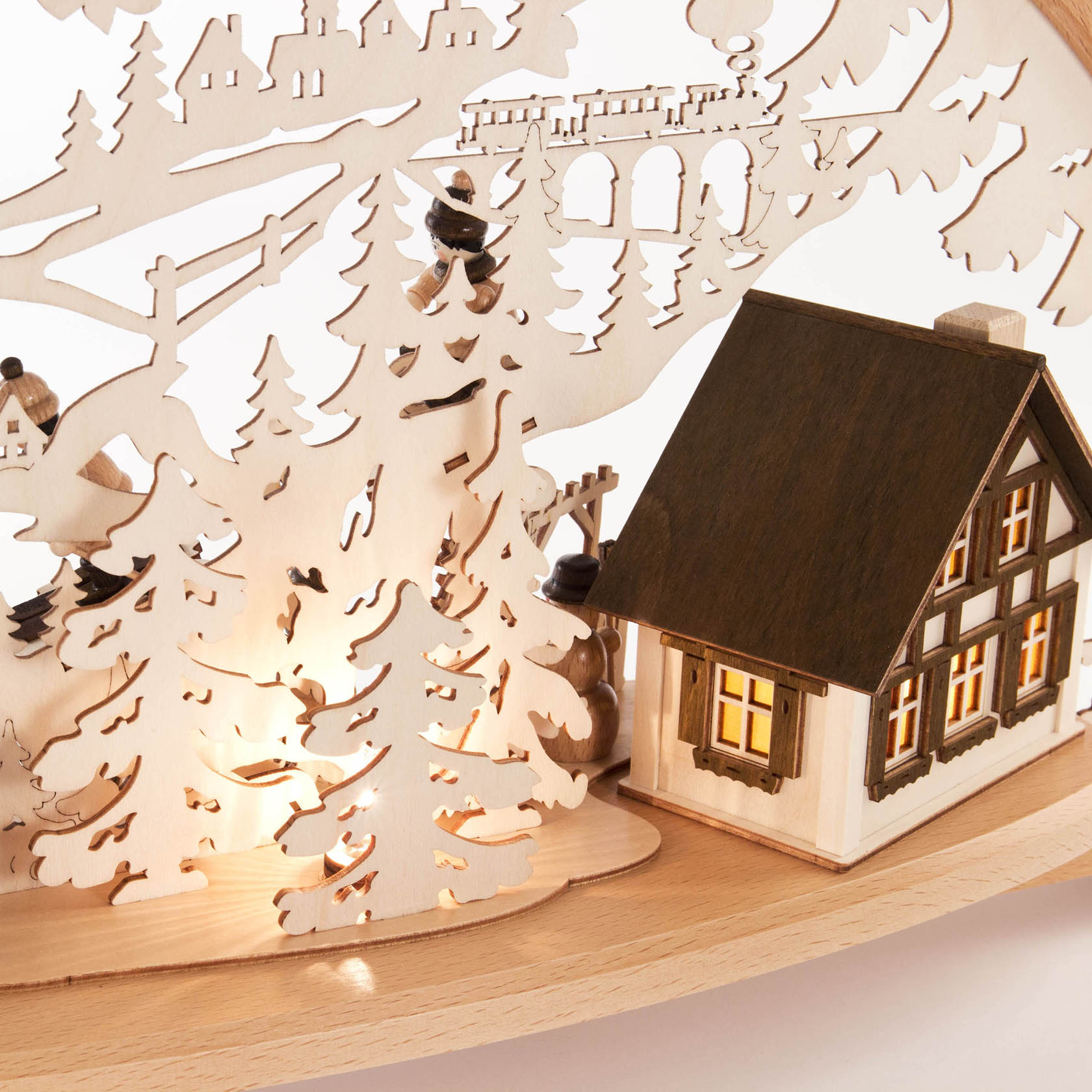 Wooden arch with a carved house and figures skiing, electrically lit with an illuminated building.