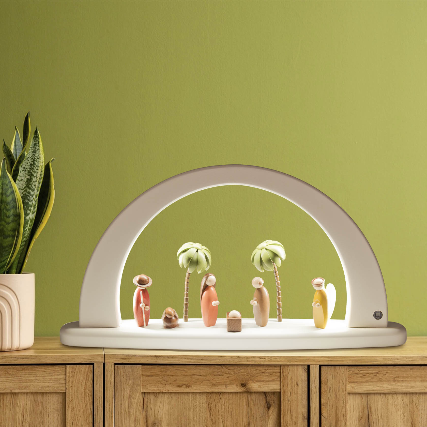 A white arch with LED lighting features a colorful nativity scene, including figures of Mary, Joseph, baby Jesus, three wise men, and two palm trees.
