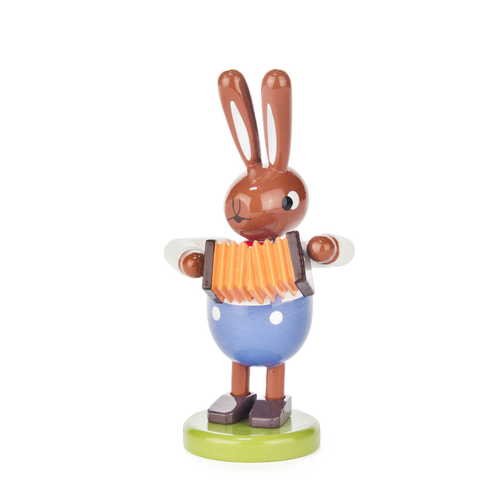 A small wooden figure of a brown rabbit wearing blue pants, holding a colorful accordion, standing on a green base. im Dregeno Online Shop günstig kaufen