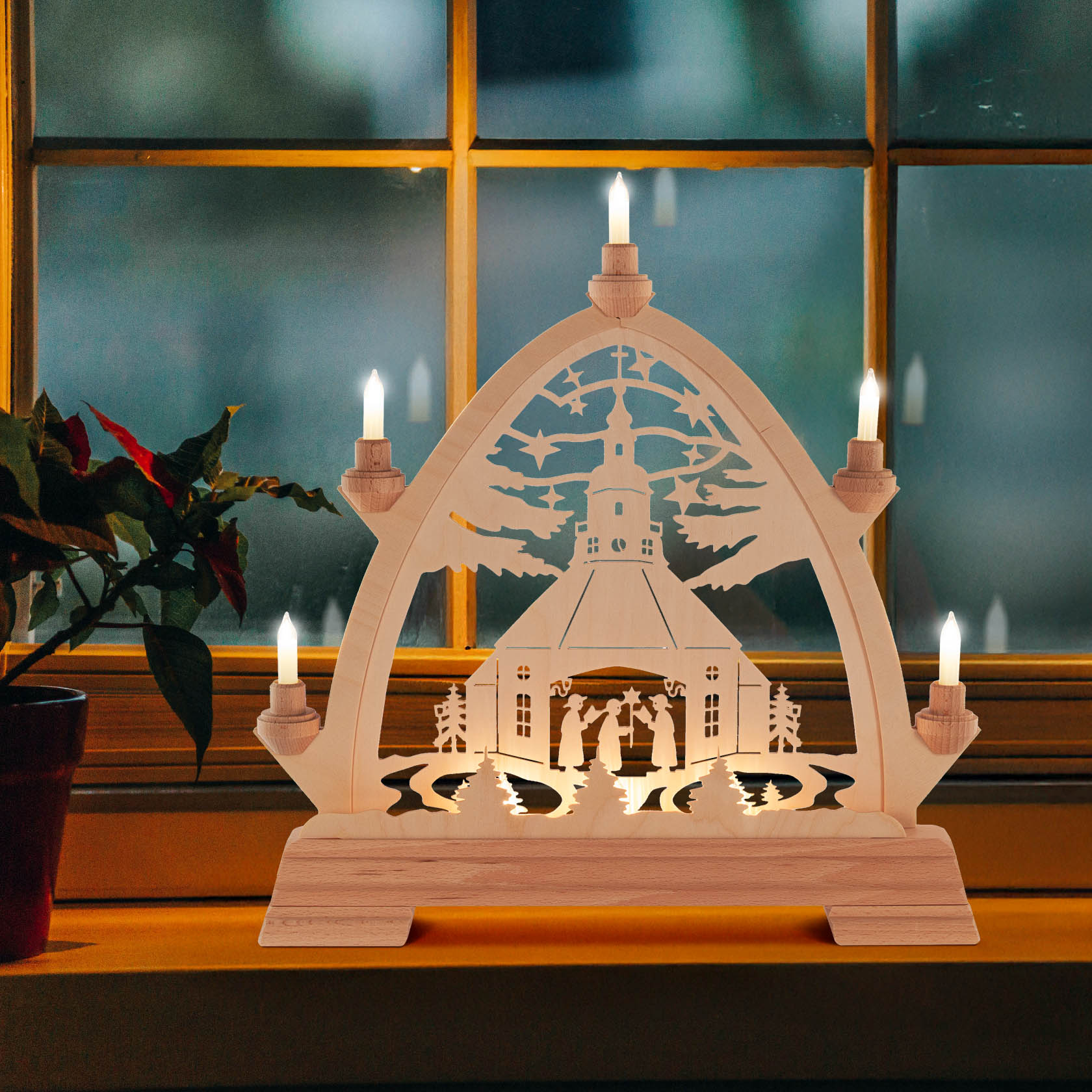 A wooden arch with a Gothic arch design displaying the Seiffen Church and Carollers, illuminated with small electric candles.