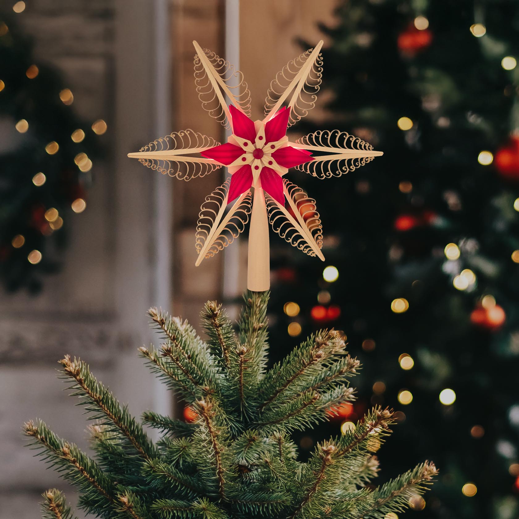 Red and natural colored star-shaped tree topper with electric lighting, 32 cm in diameter, placed on top of a Christmas tree.
