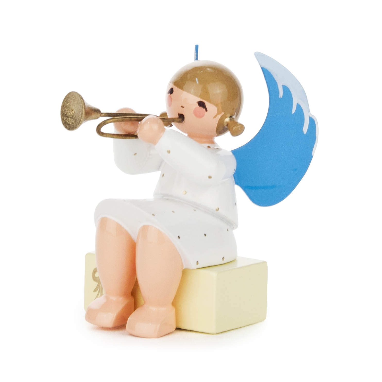 A figurine of an angel with a brown bob haircut, blue wings, wearing a white dress with small dots, sitting on a yellow gift box, playing a trumpet.