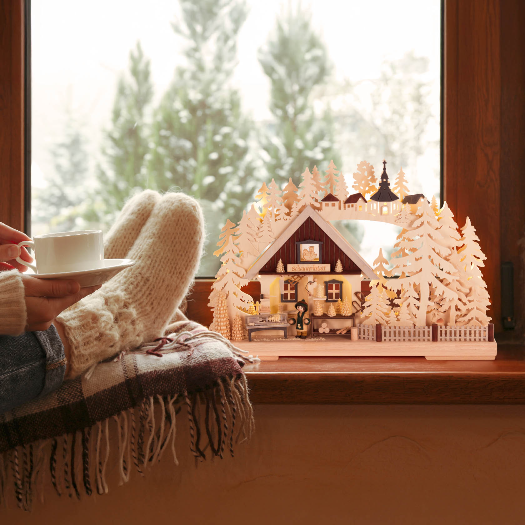 A decorative arch with a craftsman scene, featuring a wood turner with a lathe, surrounded by illuminated trees, set on a windowsill.