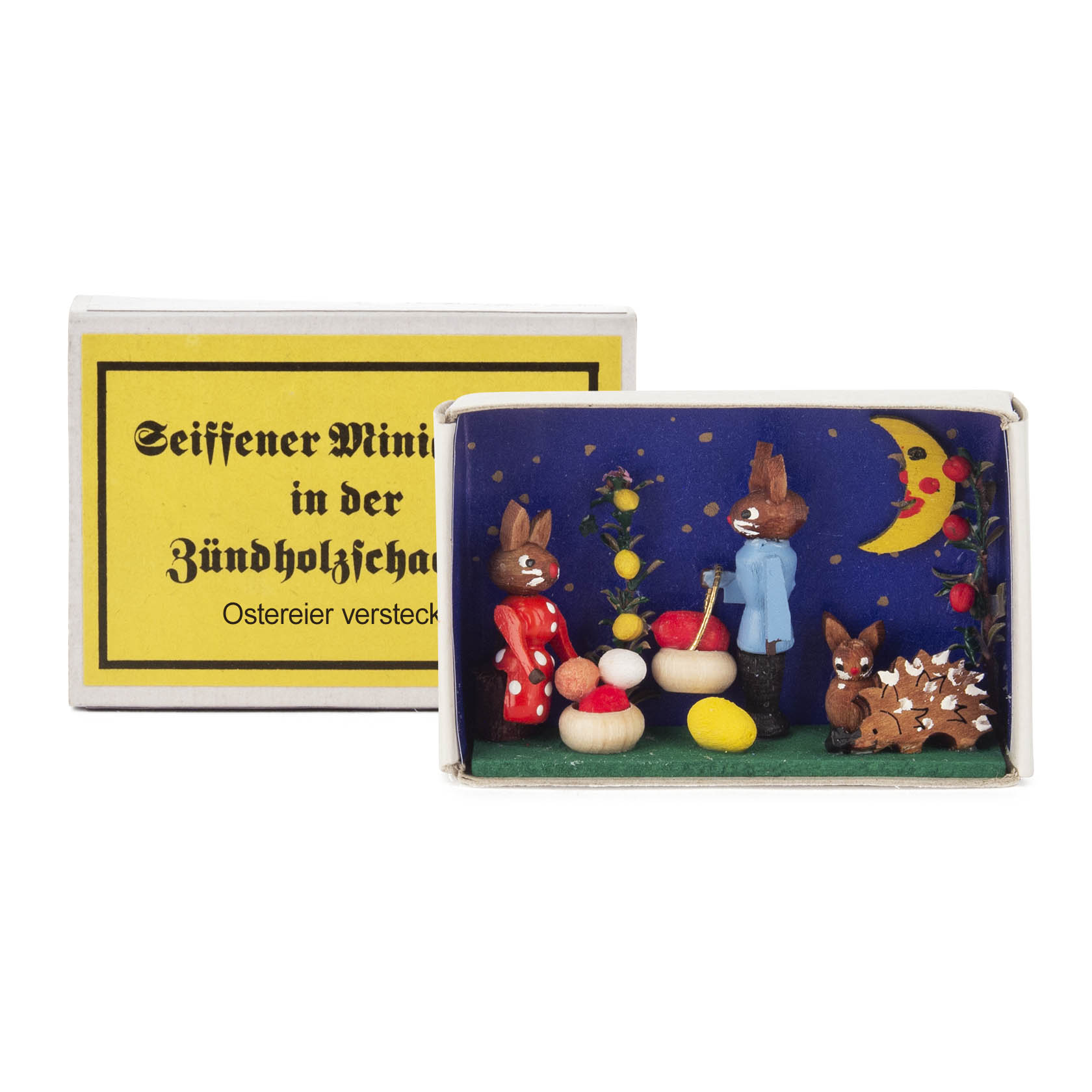 A matchbox diorama showing two bunny figures and a hedgehog with Easter eggs against a night sky. im Dregeno Online Shop günstig kaufen