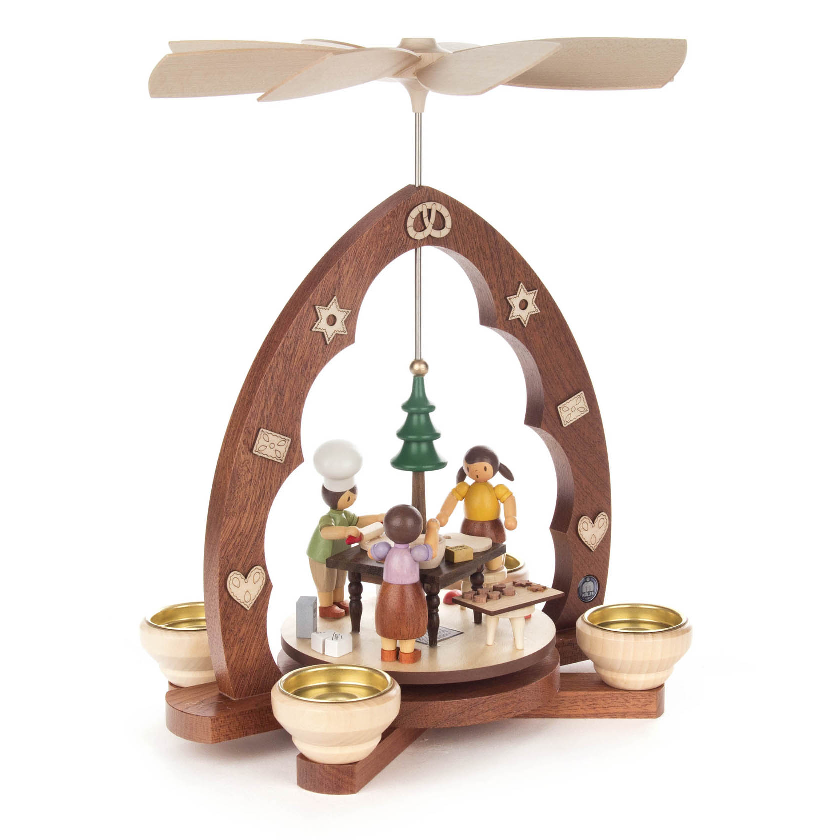 Holzpyramide mit Figuren in einer Weihnachtsbäckerei: Zwei Bäcker mit Mützen arbeiten an einem Tisch. Ein Weihnachtsbaum steht in der Mitte.