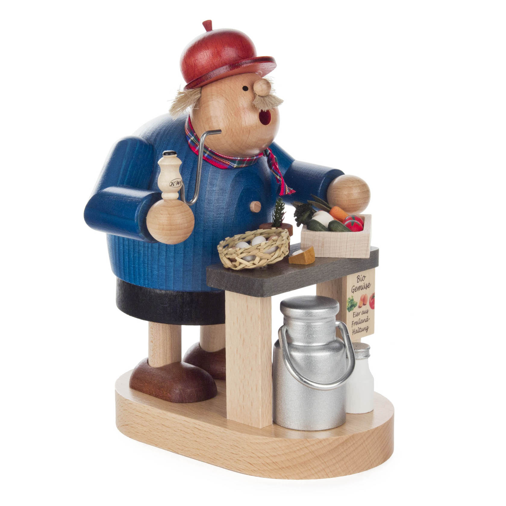 A wooden smoker figurine of an organic farmer holding a milk bottle, standing by a table with vegetables and milk cans, wearing a blue coat and red hat.