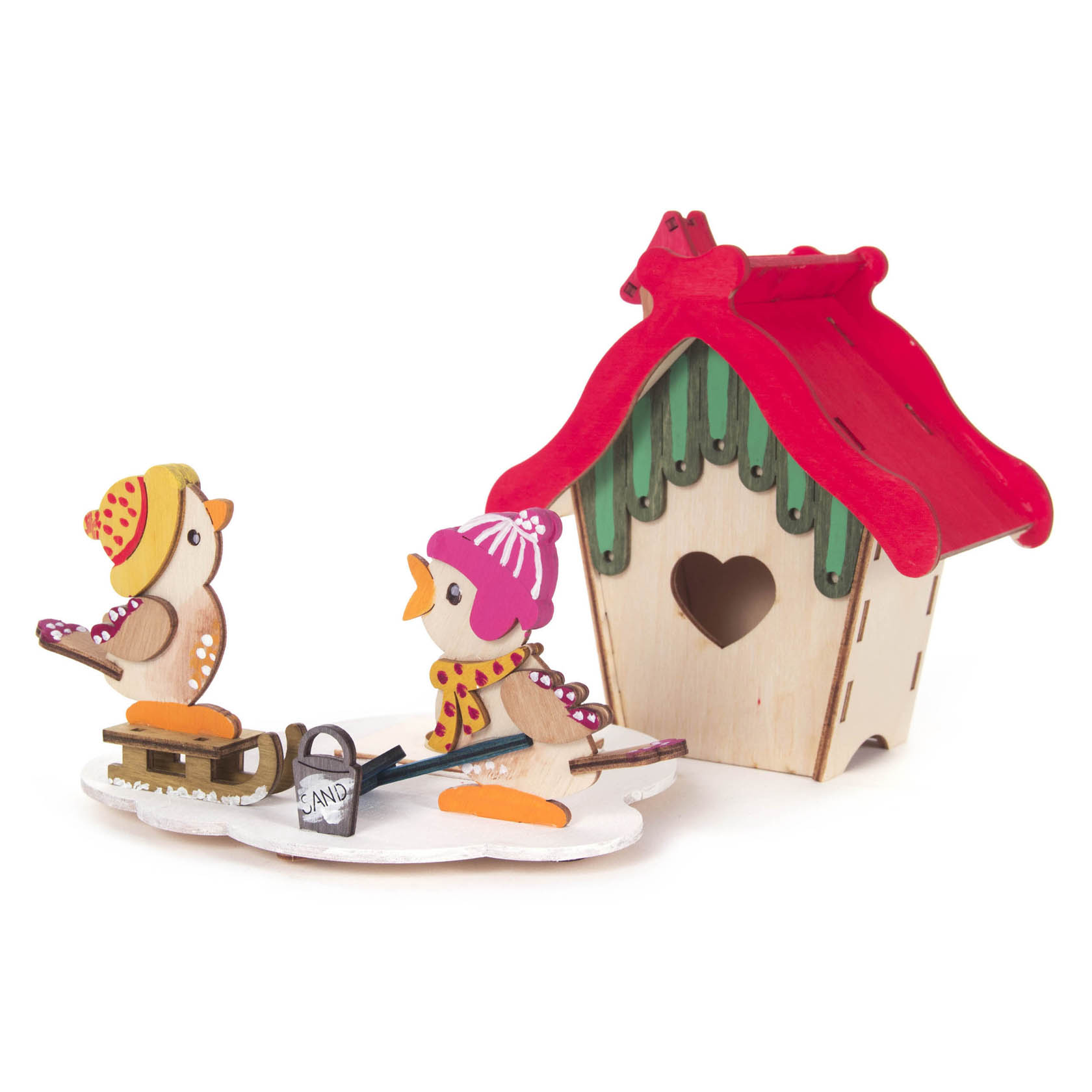 Ein Bastelset bestehend aus einem kleinen Holzräucherhaus mit rotem Dach und grünem Giebel, daneben zwei Vogel-Figuren mit Winterkleidung und Taschen.