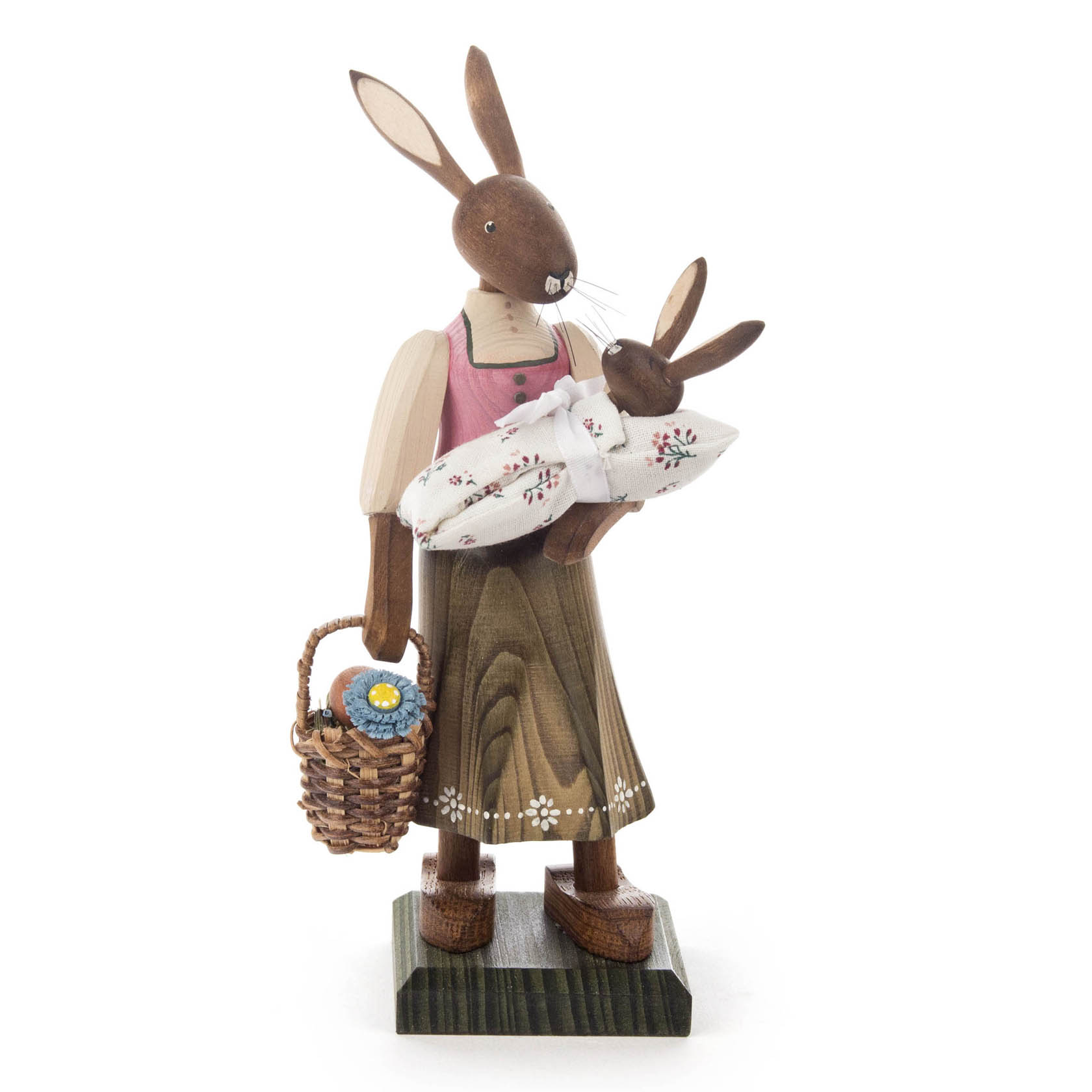 A wooden figurine of a large female rabbit wearing a pink dress and holding a wrapped baby rabbit. She carries a basket with a blue flower. im Dregeno Online Shop günstig kaufen