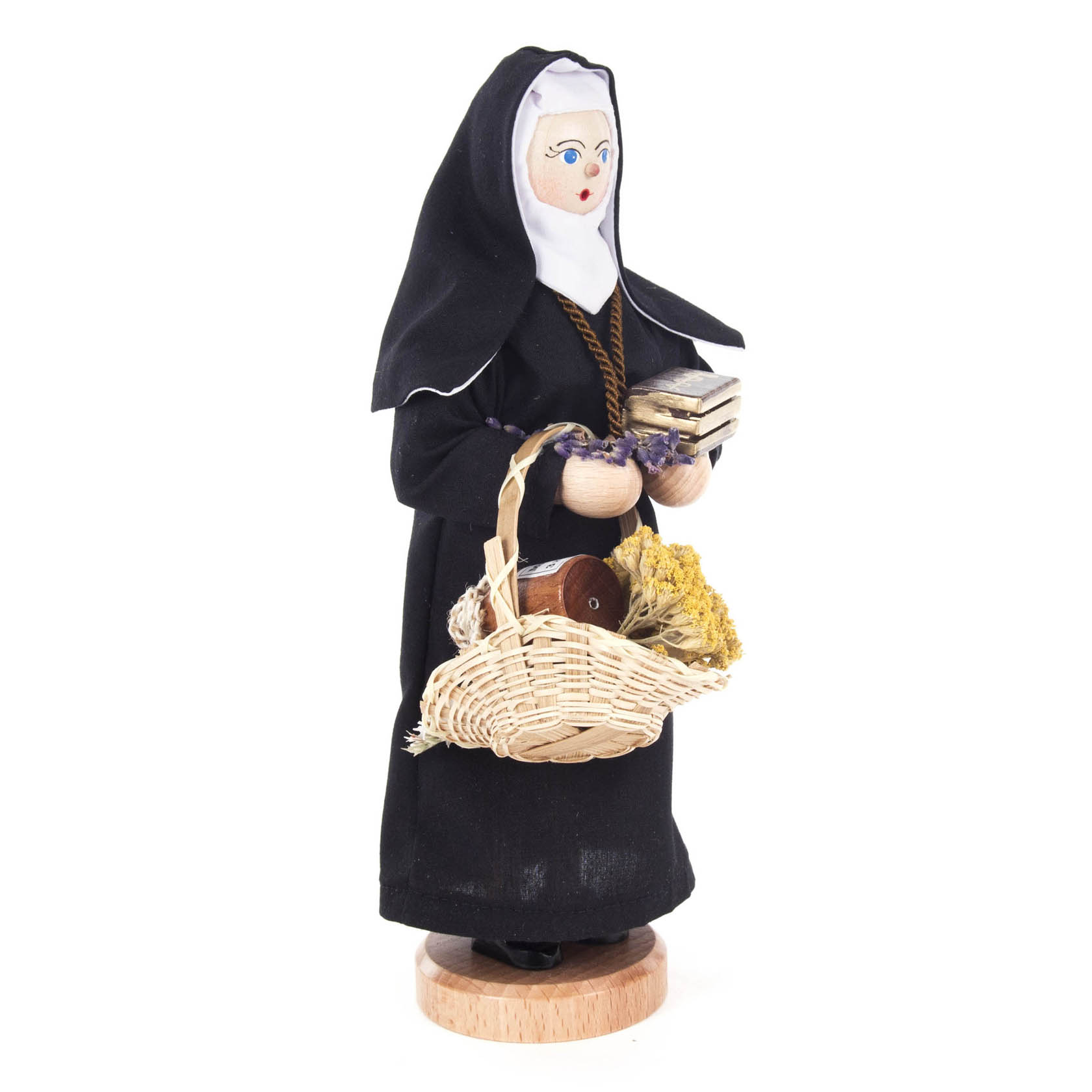 Räucherfigur einer Nonne in schwarzer Ordenstracht mit weißem Schleier, die einen Korb mit Kräutern und anderen Materialien trägt.