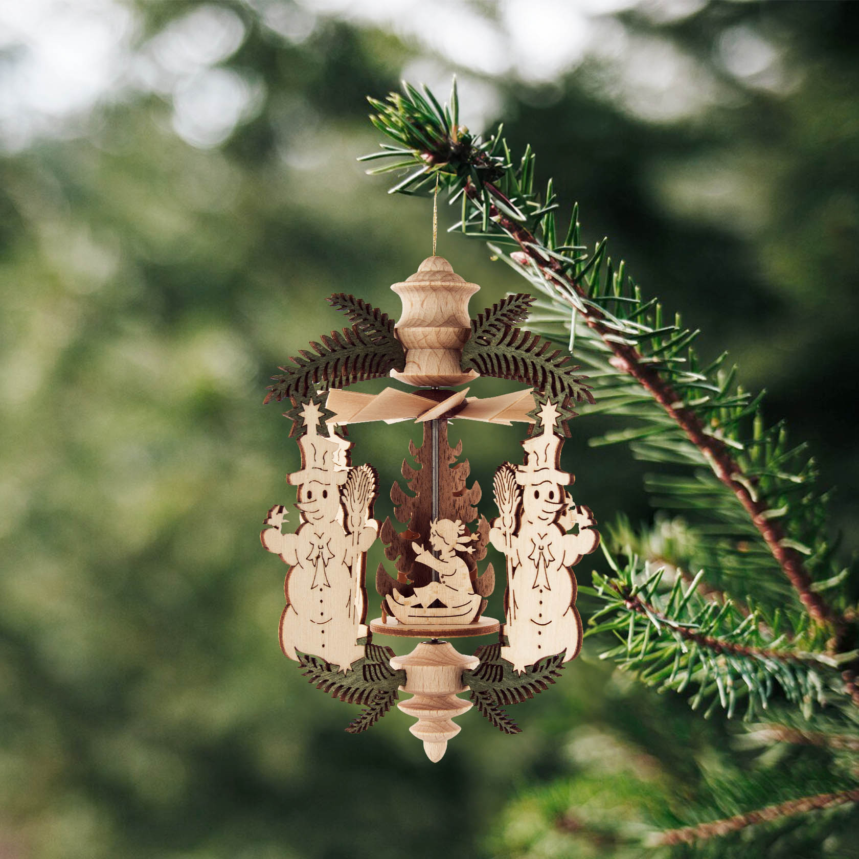 A wooden ornament with two snowmen on either side and a small figure in the center, designed to hang on a branch.