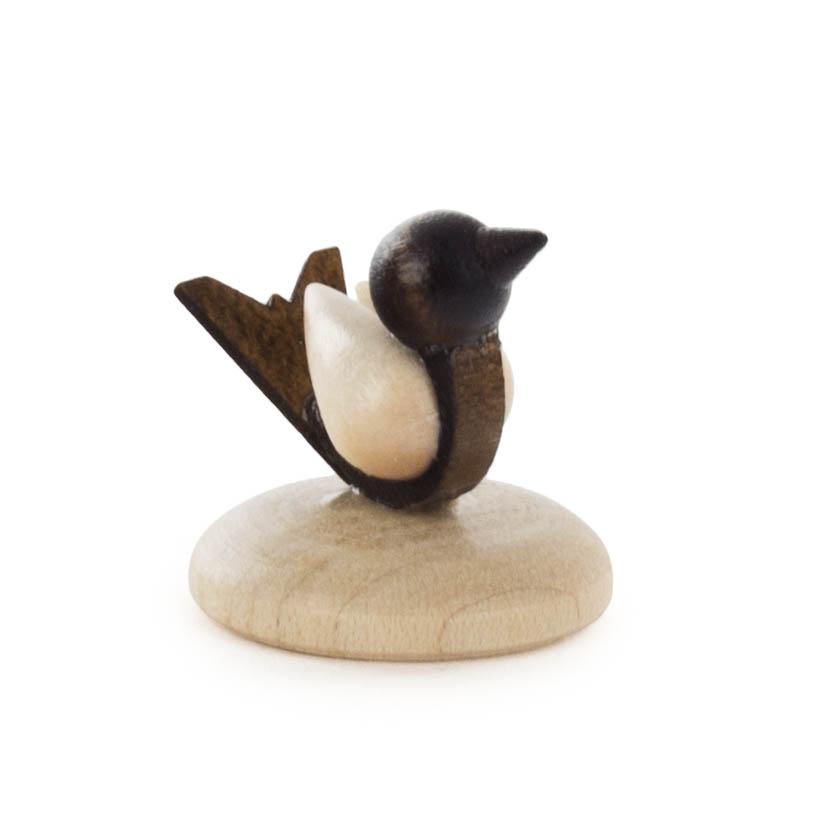 Handgefertigter kleiner Vogel aus Holz auf einem runden Sockel. Der Vogel hat einen dunklen Kopf und einen hellen Körper. im Dregeno Online Shop günstig kaufen