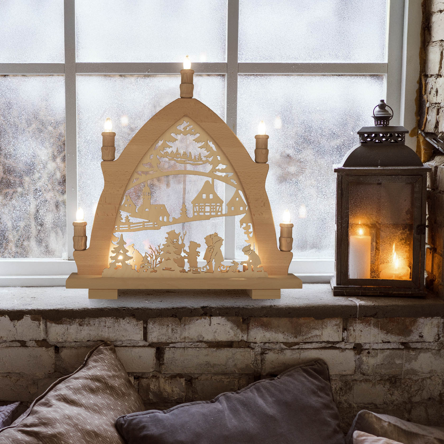 Wooden arch candelabra with LED lights featuring winter children and a snowy village scene, placed on a windowsill with a lit lantern beside it.