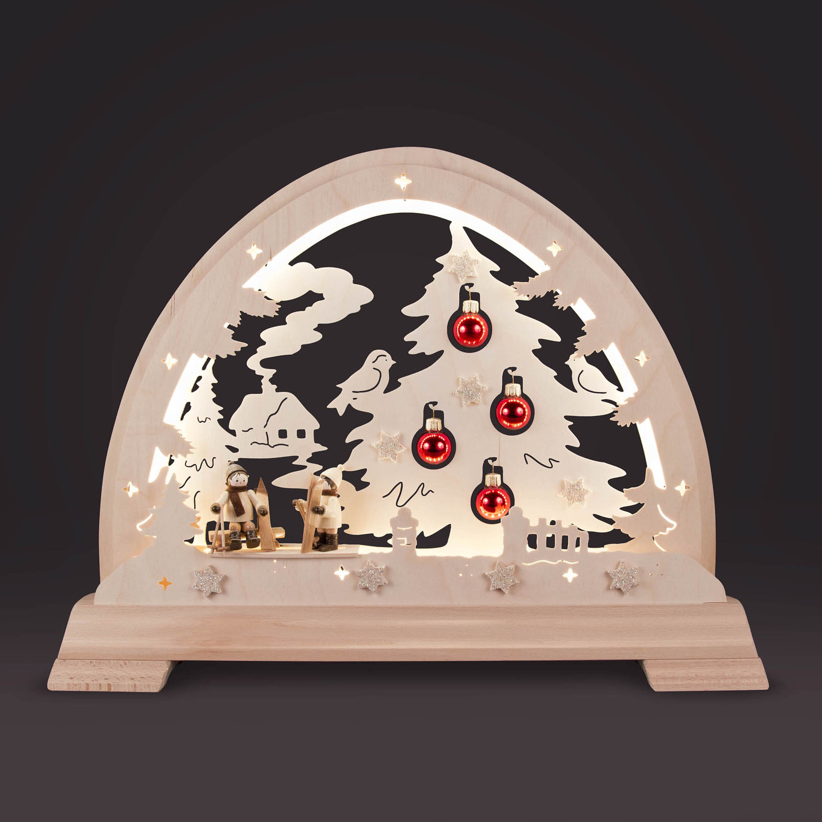 Wooden arched decoration featuring a skier, Christmas tree with red baubles, and LED lighting against a black background.