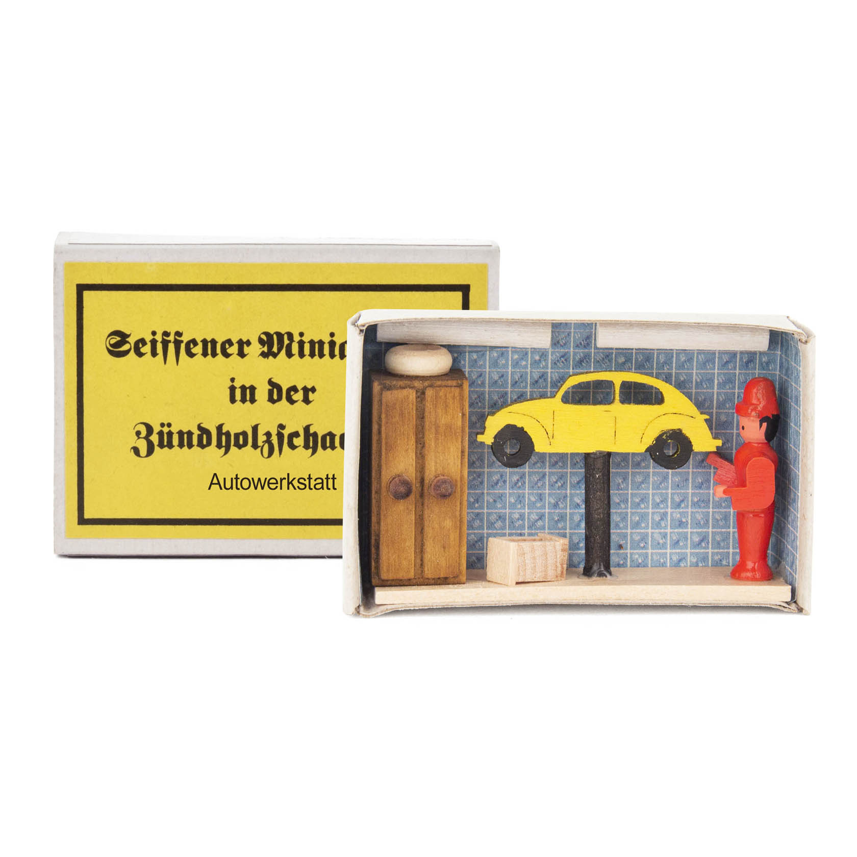 A miniature garage inside a matchbox with a wooden wardrobe, a lift with a yellow car on it, and a red figure of a mechanic. im Dregeno Online Shop günstig kaufen