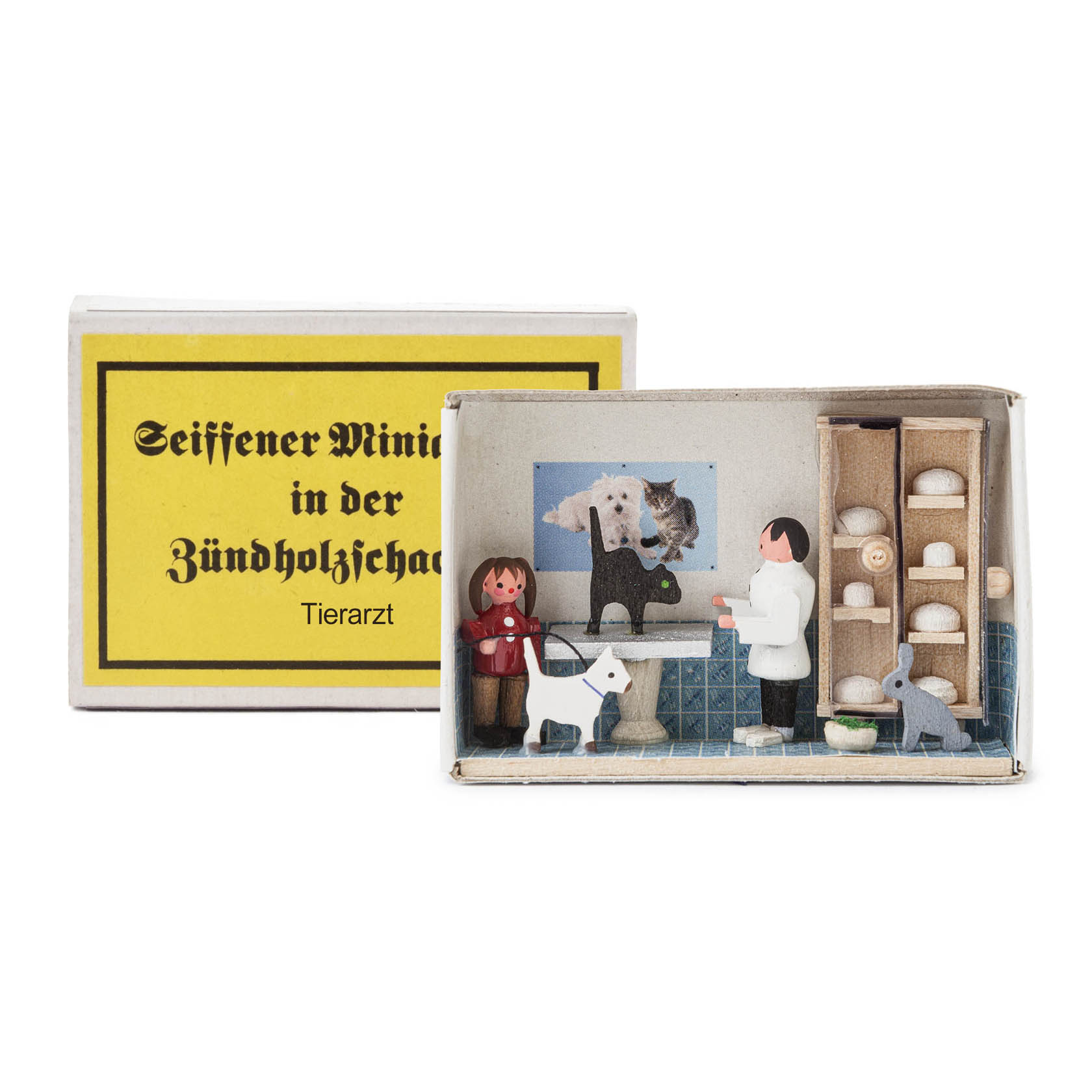 A miniature veterinary clinic scene inside a matchbox, featuring a male veterinarian, a woman, a dog, and a cat. im Dregeno Online Shop günstig kaufen