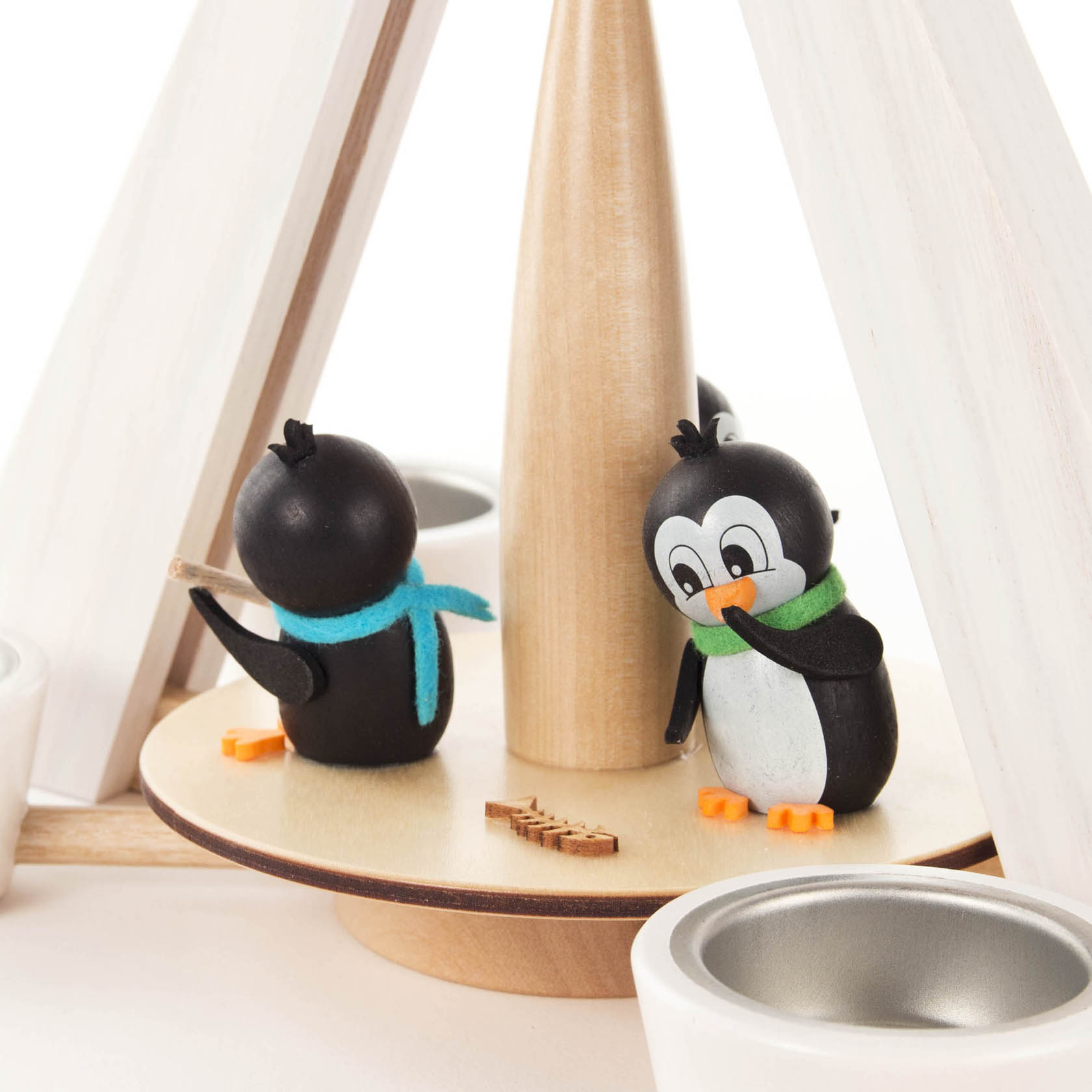 Zwei handgefertigte Pinguinfiguren aus Holz stehen auf einer drehbaren Platte einer weißen Pyramide, die für Teelichte geeignet ist.