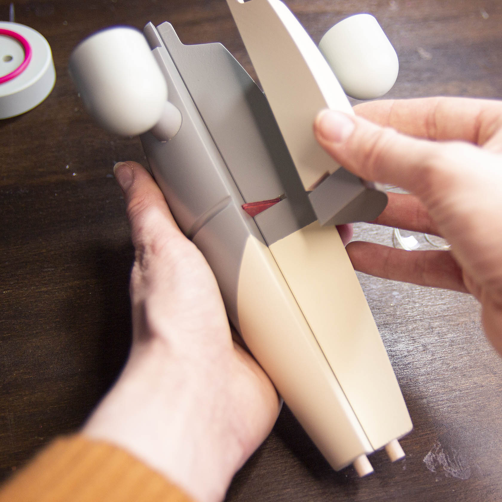 Zwei Hände halten eine weiße Vorrichtung aus Kunststoff, die für das sichere Aufsetzen von Engeln auf Kerzen mit 14mm Durchmesser verwendet wird.