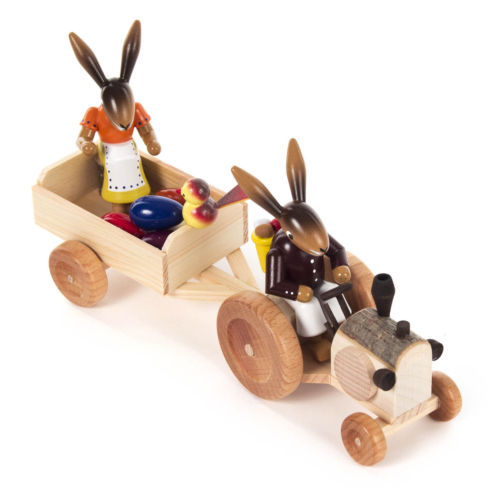 Wooden bunny figure driving a tractor with a bunny in an orange dress in the trailer carrying colorful eggs and apples.