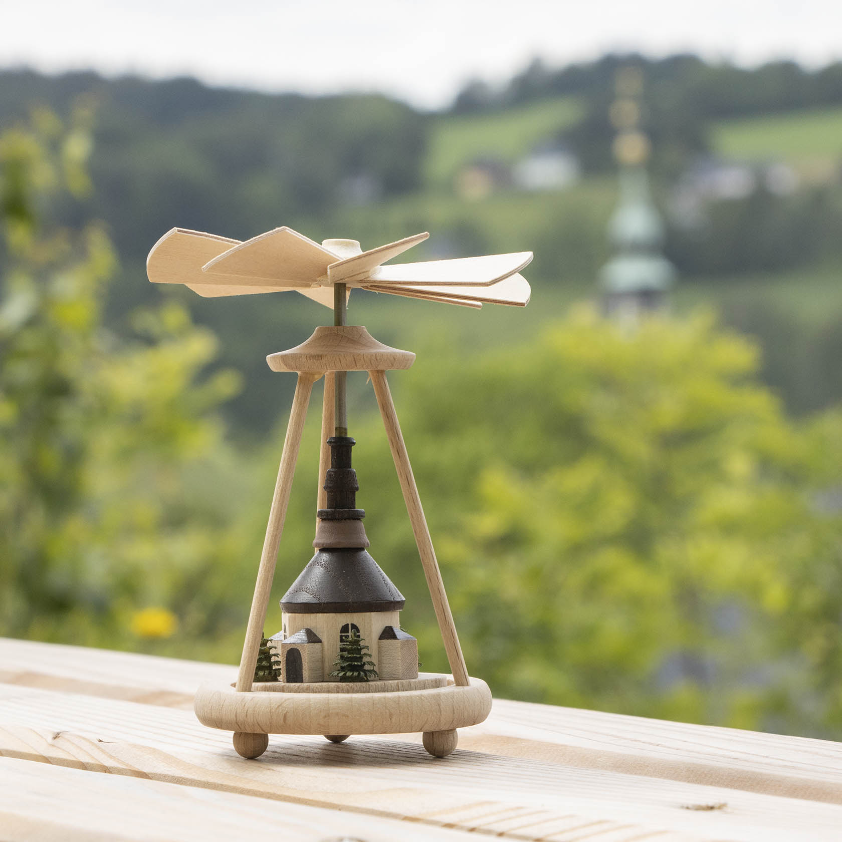 A wooden heat-powered carousel with a model of the Seiffen Church at its base, designed with a propeller on top to rotate with warmth.