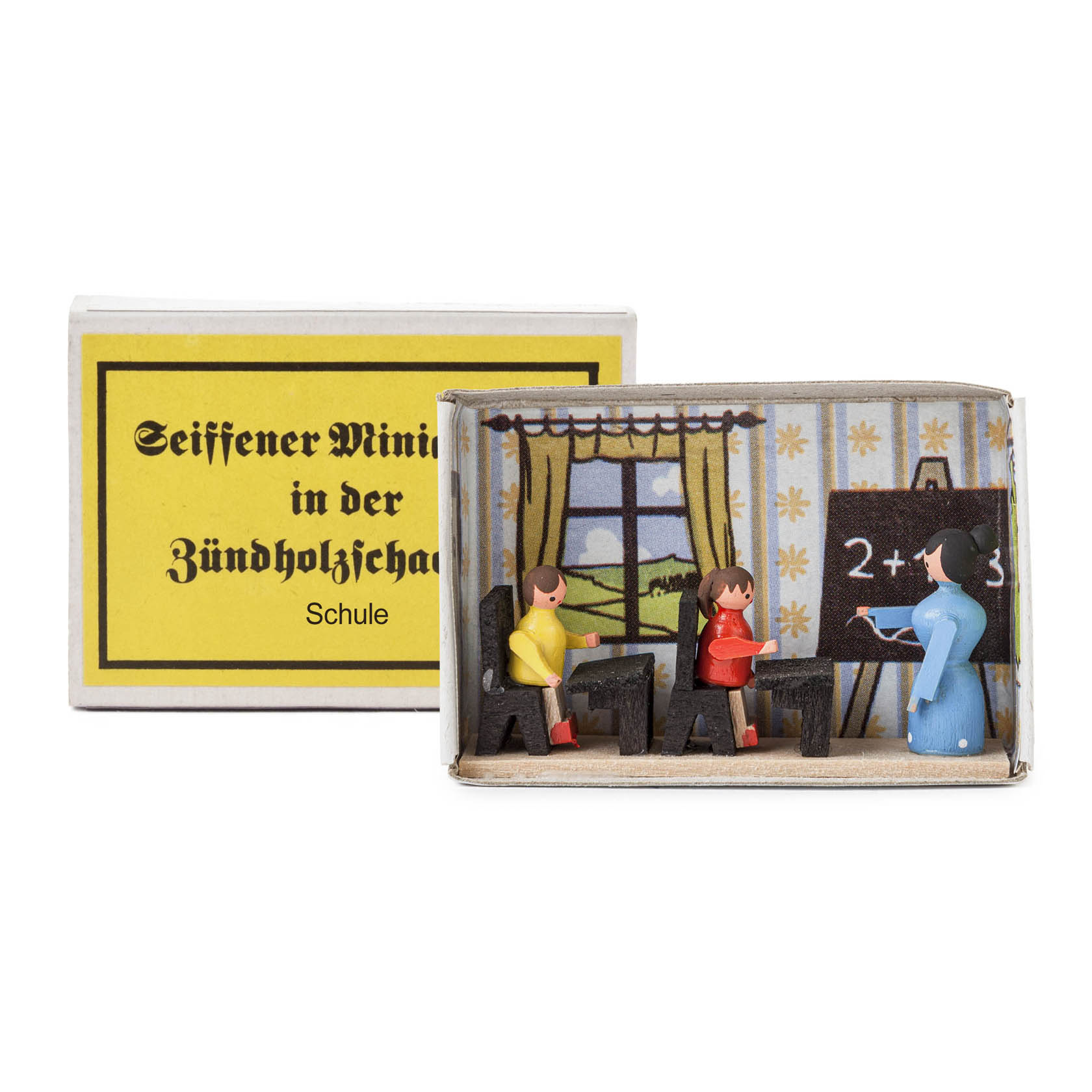 Miniature school scene in a matchbox with two children sitting at desks and a teacher standing in front of a blackboard with math equation 2+3=.