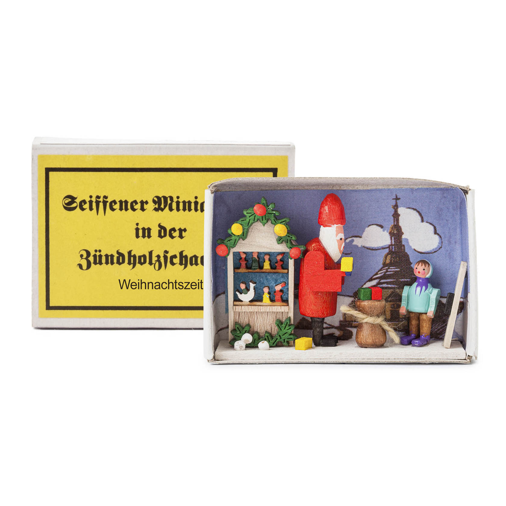 A matchbox scene depicting Christmas time, featuring a mini Santa figure, a child, and a decorated tree inside a small open box. im Dregeno Online Shop günstig kaufen