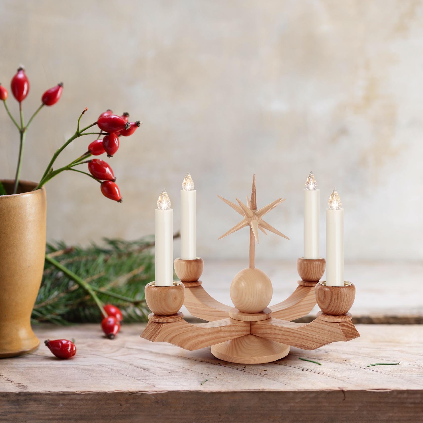 Ein kleiner, natürlicher Adventsleuchter mit einem zentralen Stern und vier weißen Kerzen, die in Holzhalterungen auf einem dekorativen Holzfuß stecken.