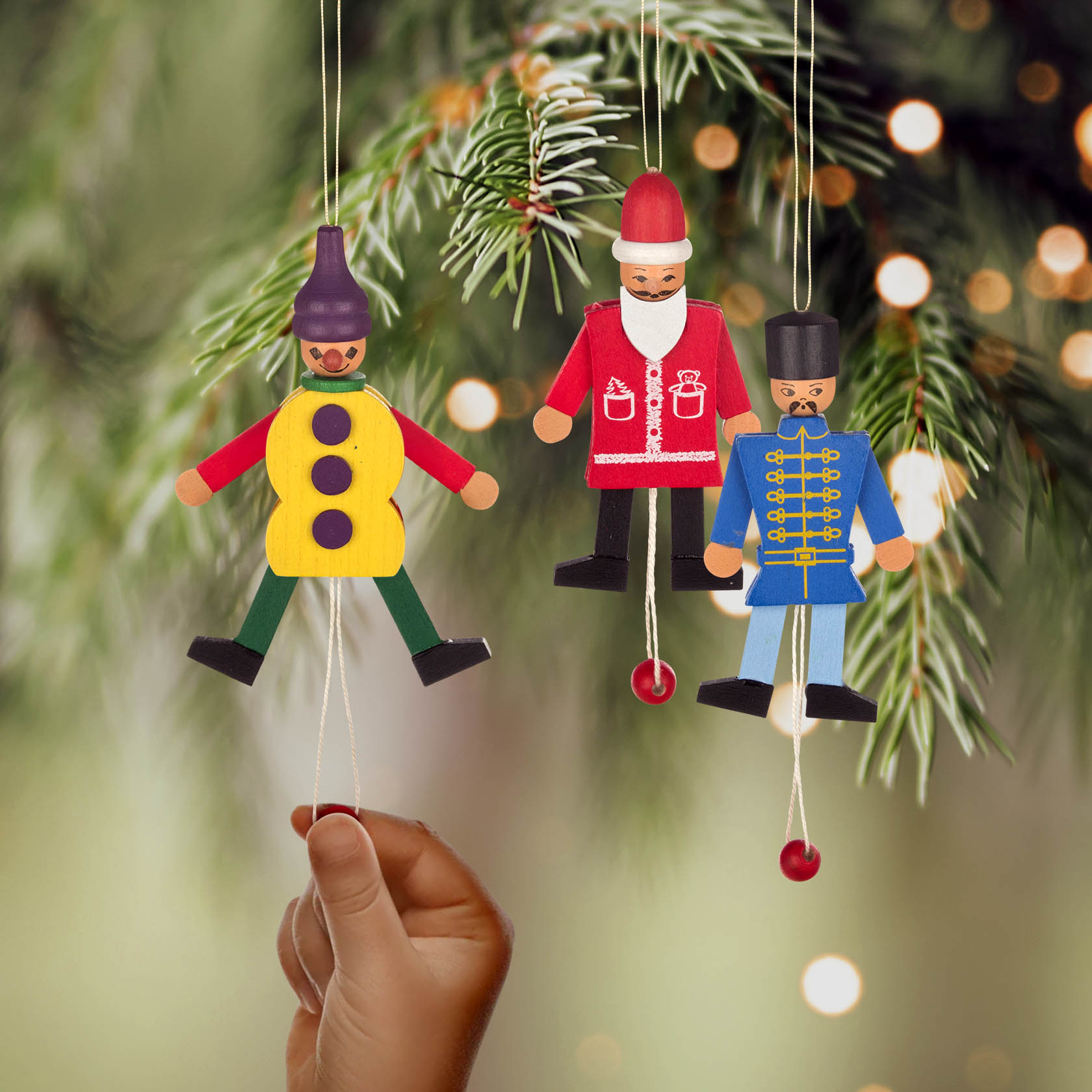 A hand pulling a string on a hanging wooden toy soldier, with two other figures: a Santa Claus and a soldier in a blue uniform.