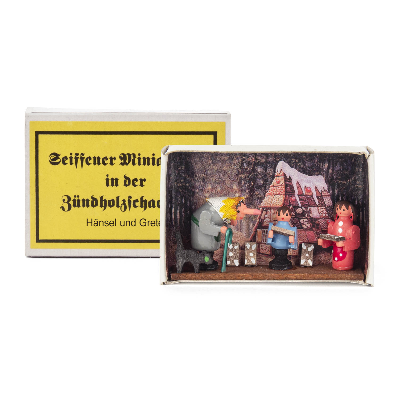 A matchbox diorama featuring Hansel and Gretel with the witch in front of a gingerbread house covered in snow. The characters are small and colorful. im Dregeno Online Shop günstig kaufen