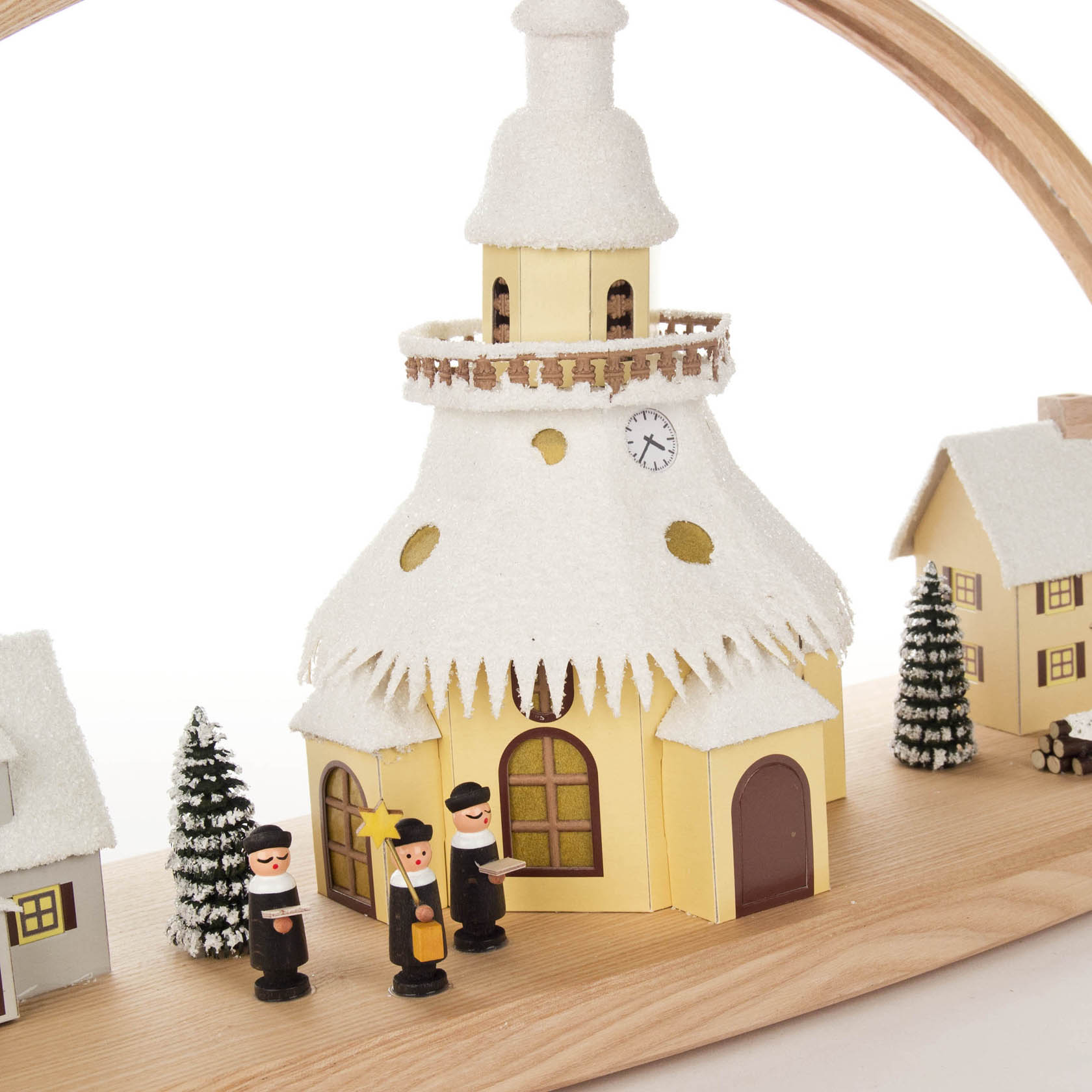 Ein Schwibbogen zeigt das Seiffener Dorf mit beleuchteter Kirche, die verschneit ist. Davor stehen drei traditionelle Holzfiguren und ein Weihnachtsbaum.